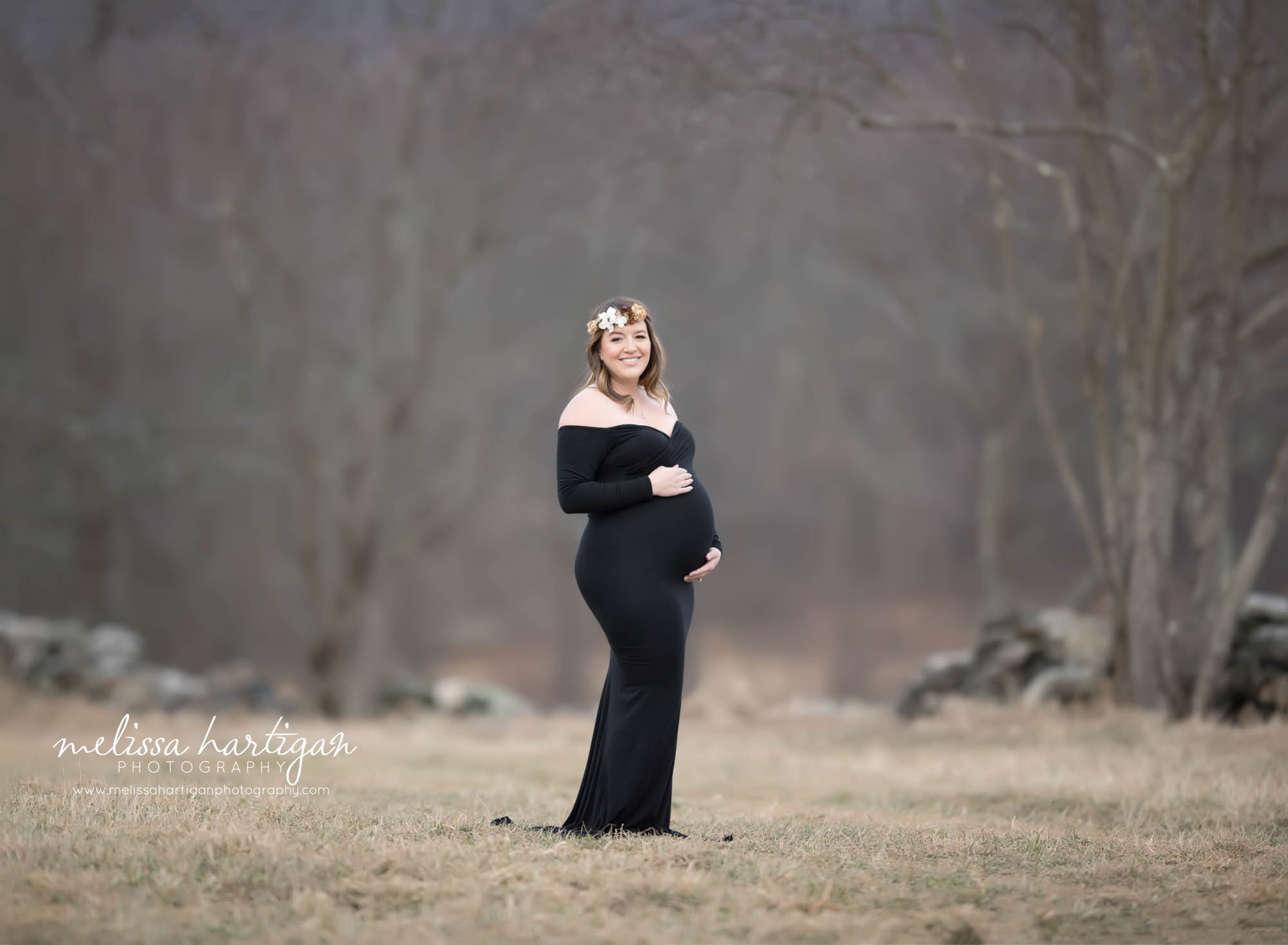 Expectant new mom wearing off the should maternity dress in black outside maternity session in January in Connecticut