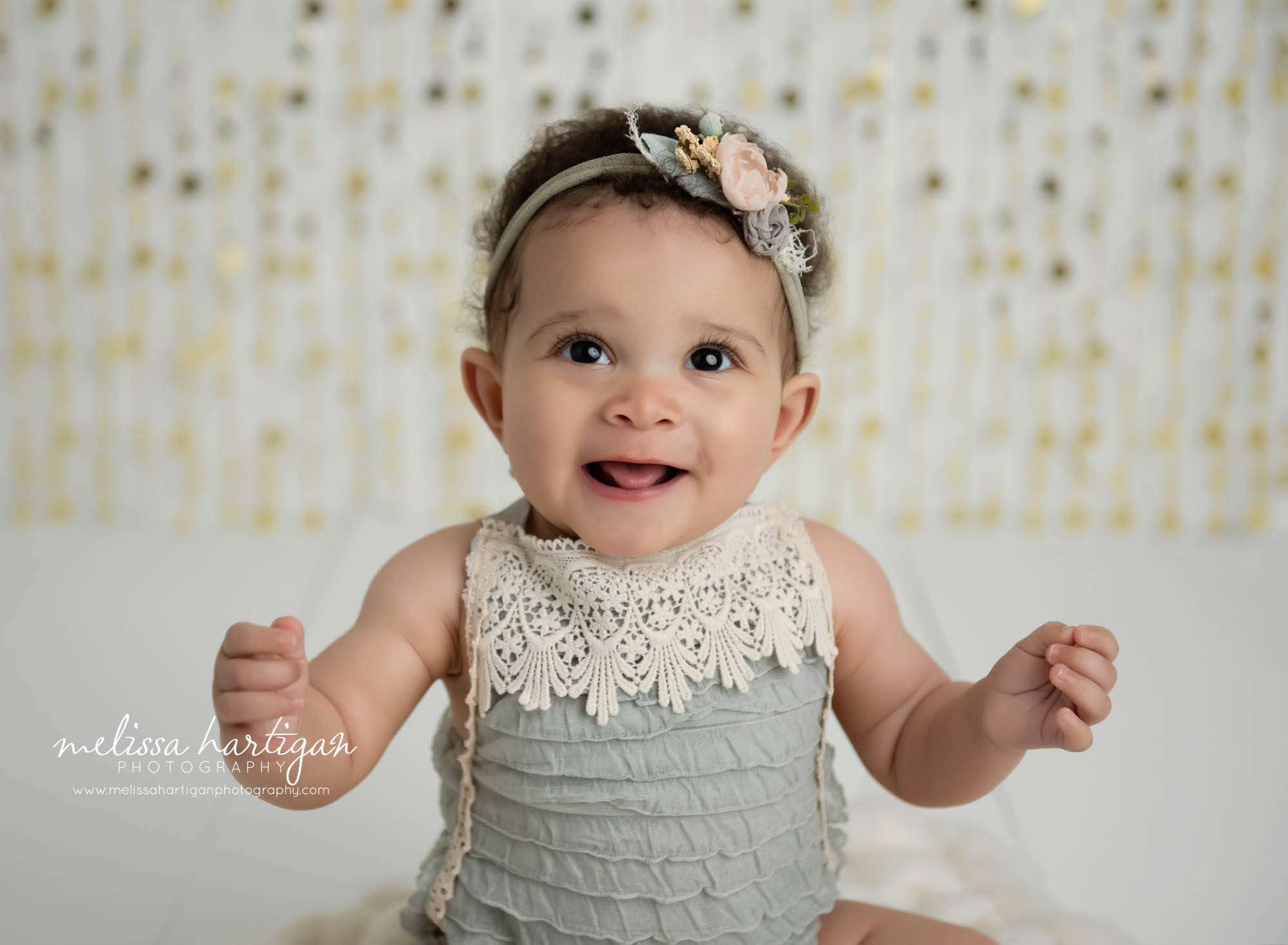 baby girl wearing muted blue with lace romper white wooden boards and gold