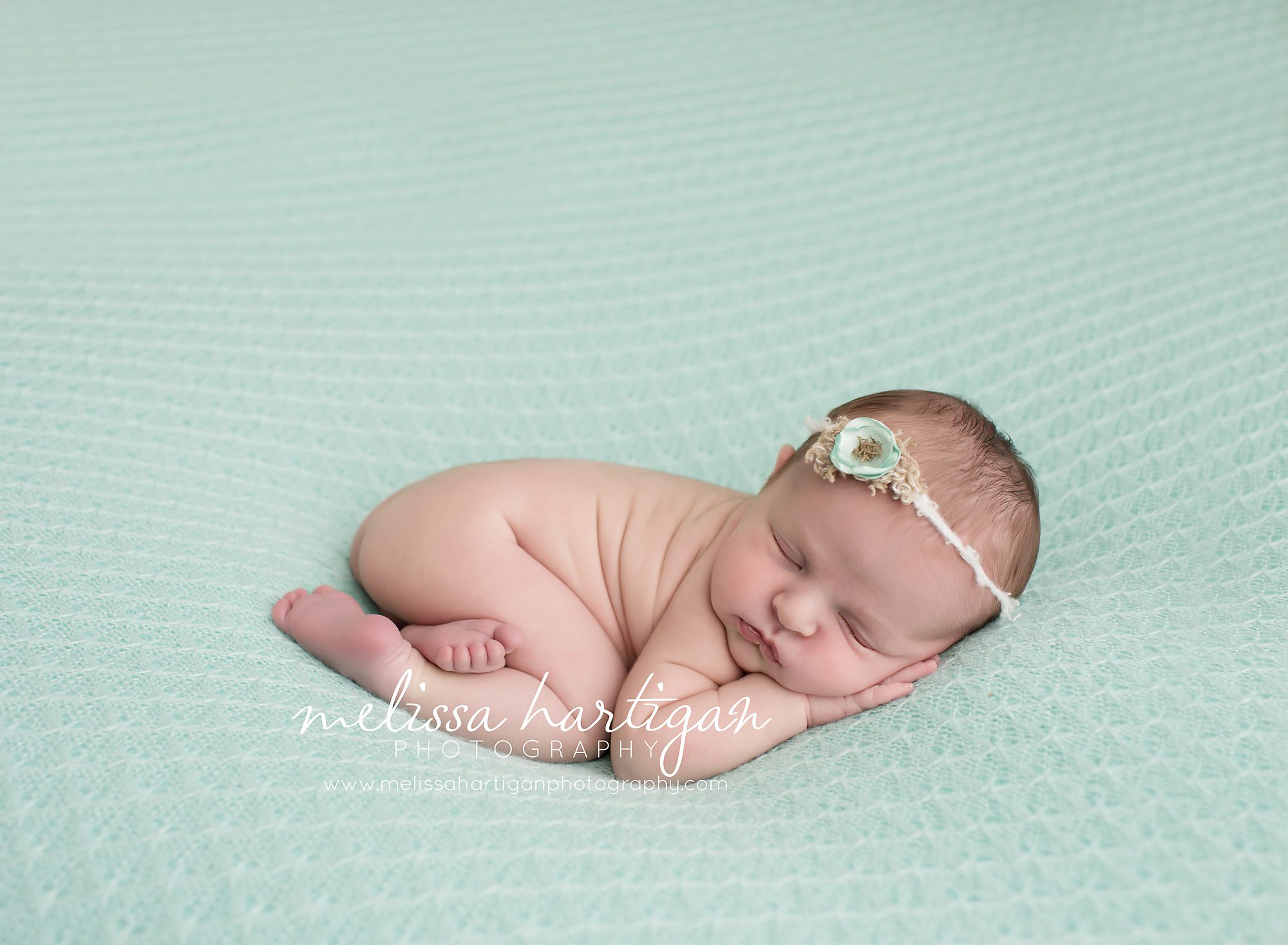 newborn baby girl sleeping on textured blanket with mini and cream colored tie back