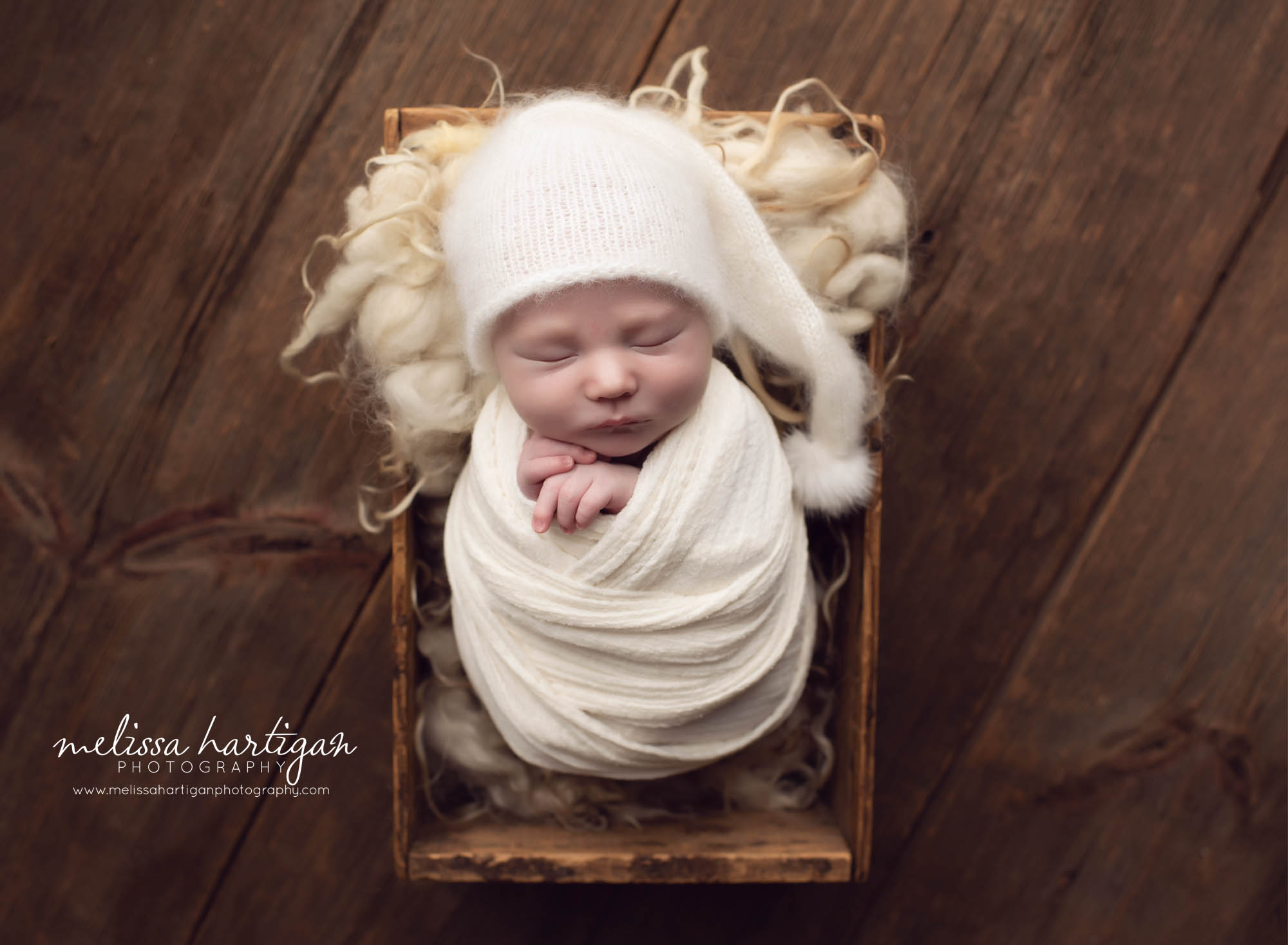 Baby boy wrapped up poised in wooden crate with rustic look cream and white tones newborn photos CT