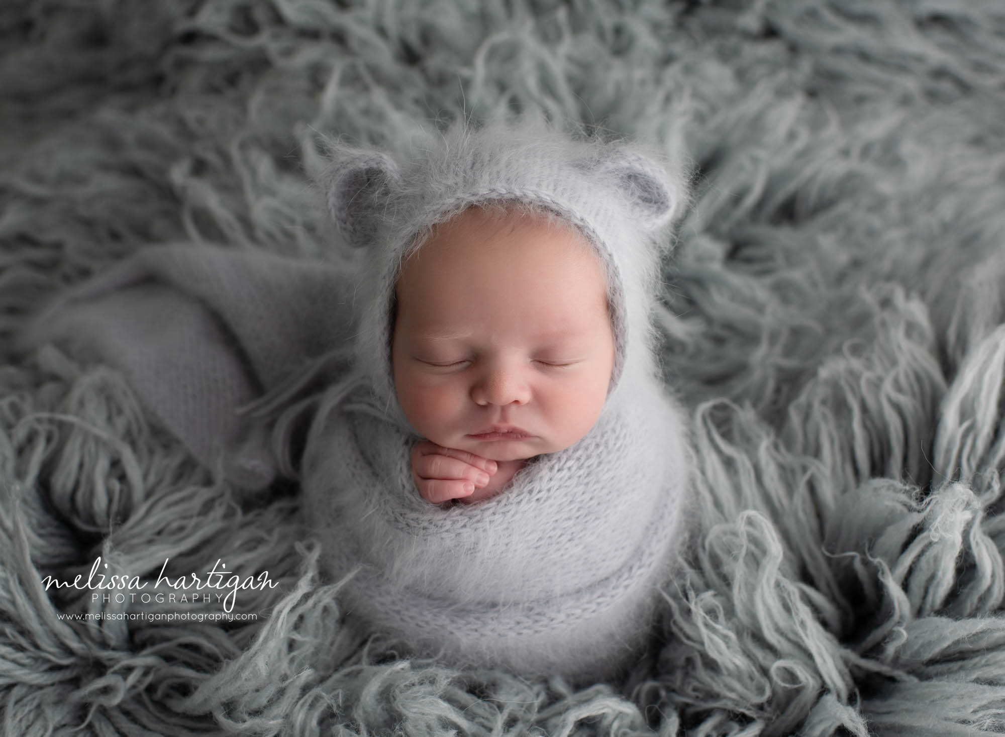 Newborn baby wrapped in angora wrap with bear bonnet in light grey