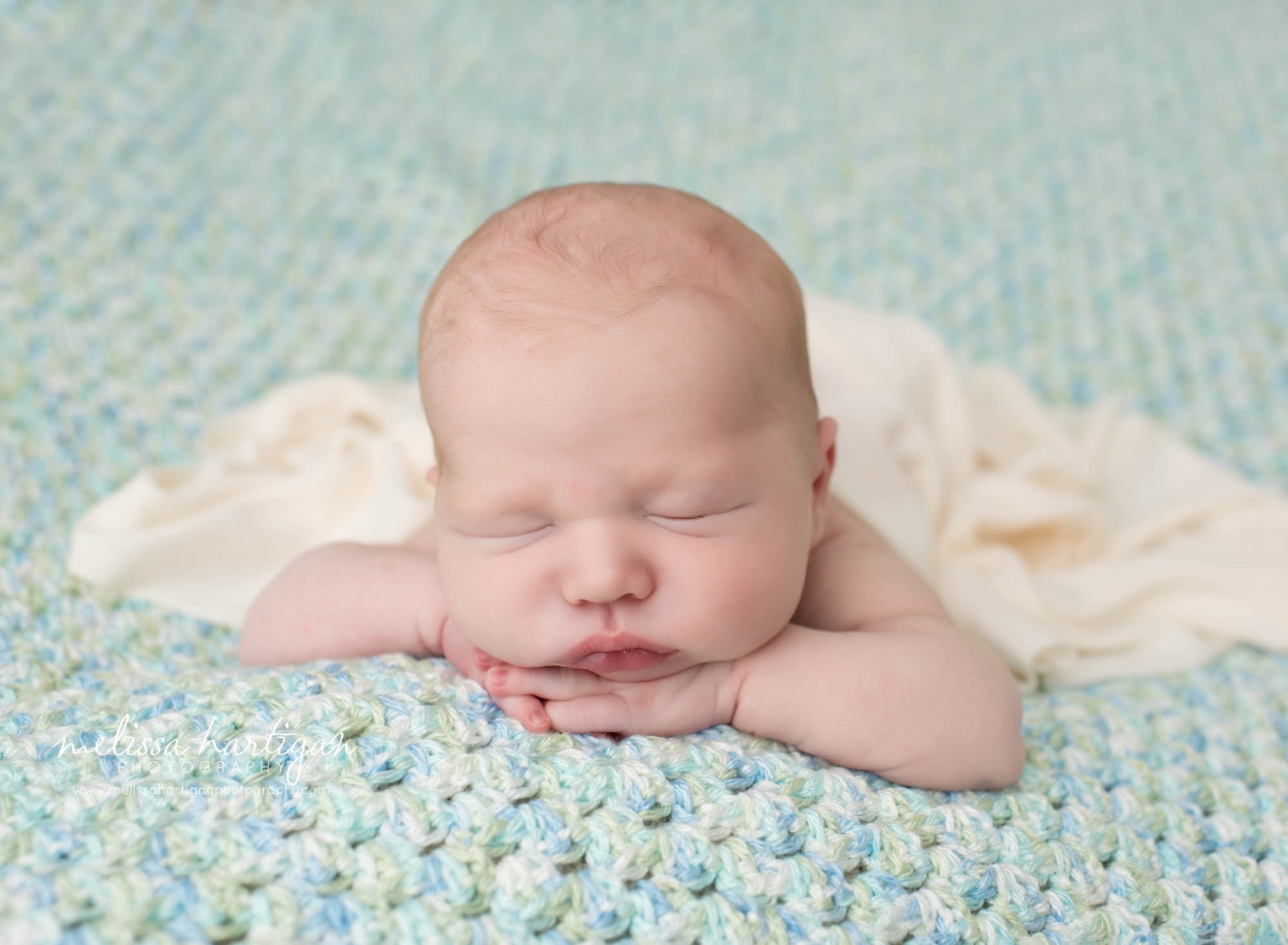 Baby boy posed on handmade knitted crocheted baby blanket with light green and light blue colors