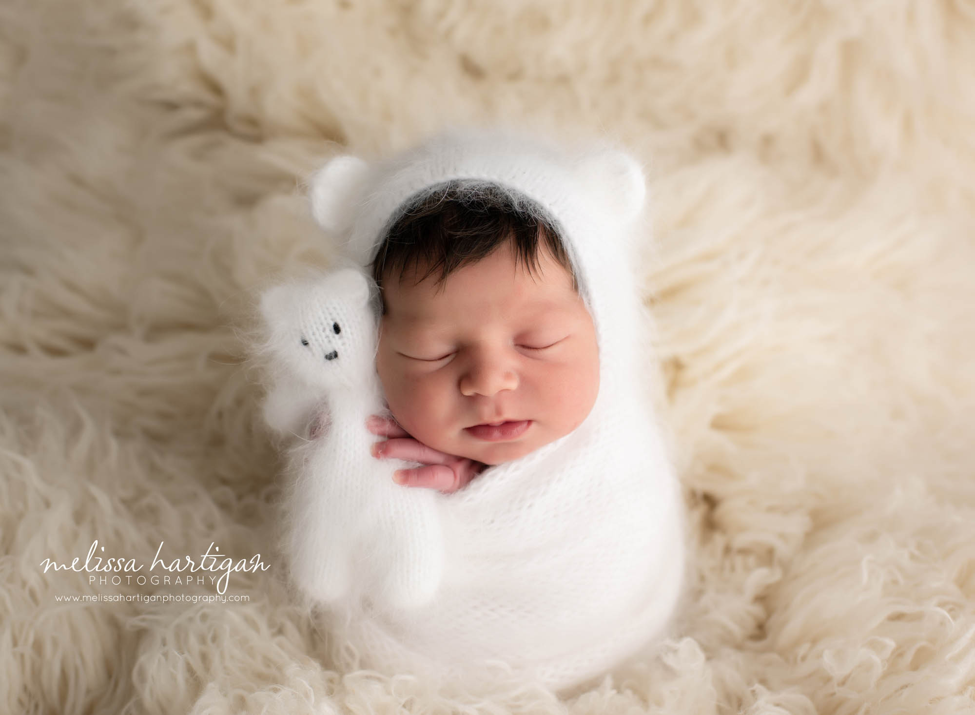 baby girl wearing knitted angora bear bonnet in white with white knitted teddy bear