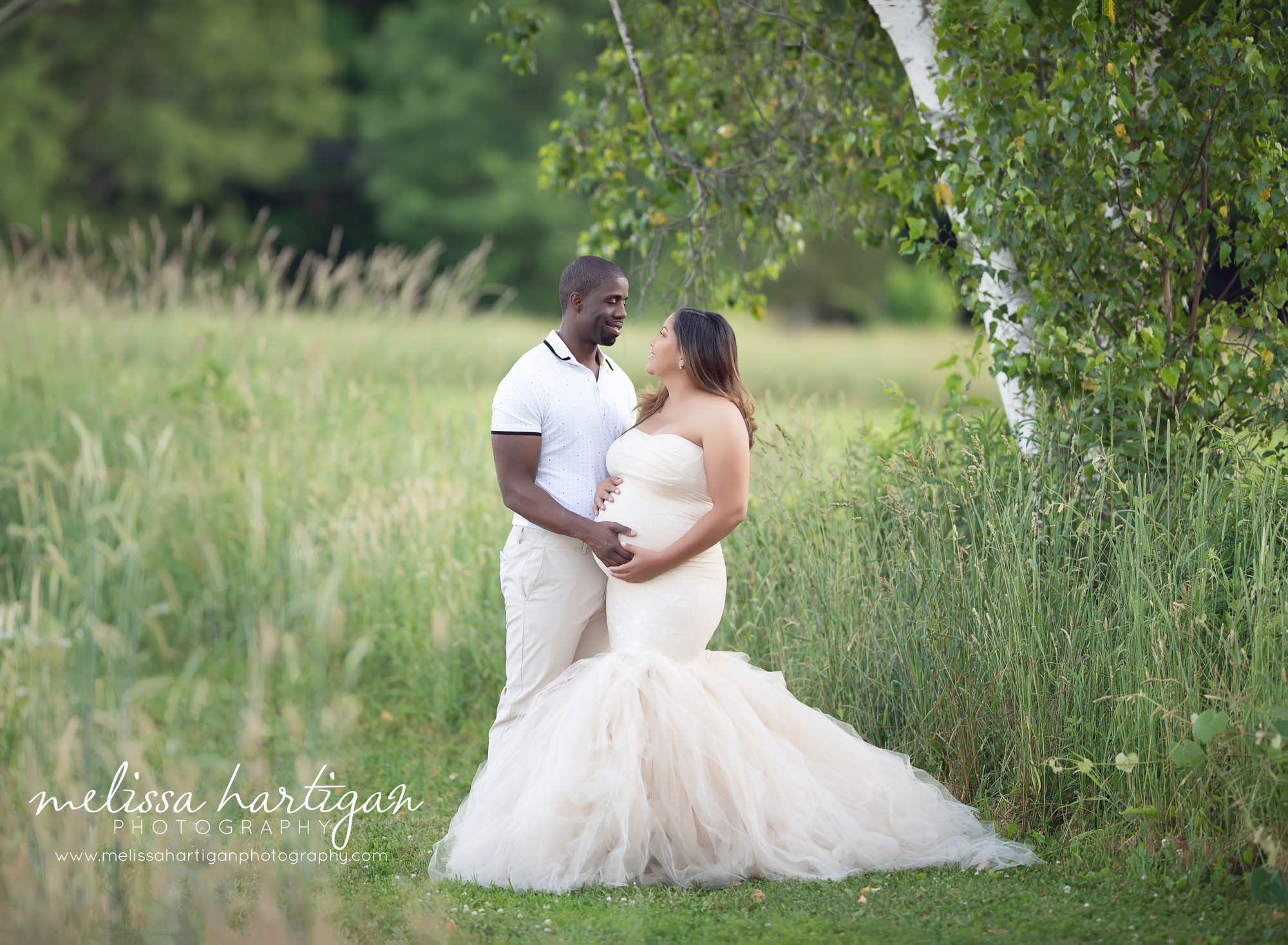 Couple standing under a tree holding moms pregnancy baby bump CT maternity newborn photographers