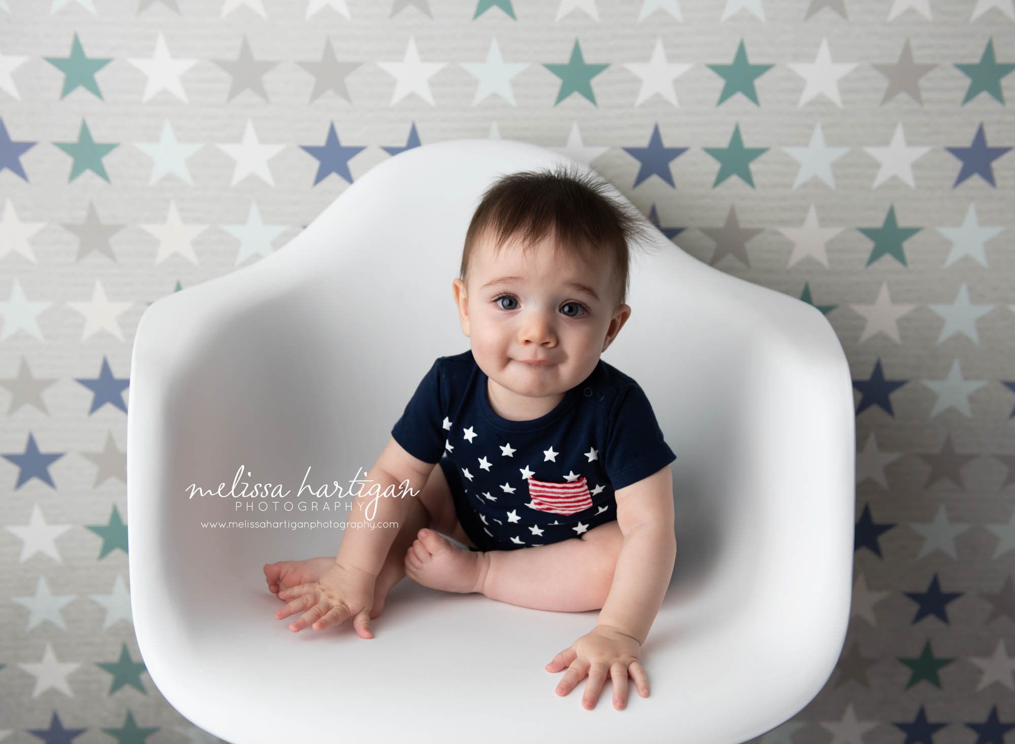 Baby boy sitting in white chair with stars backdrop
