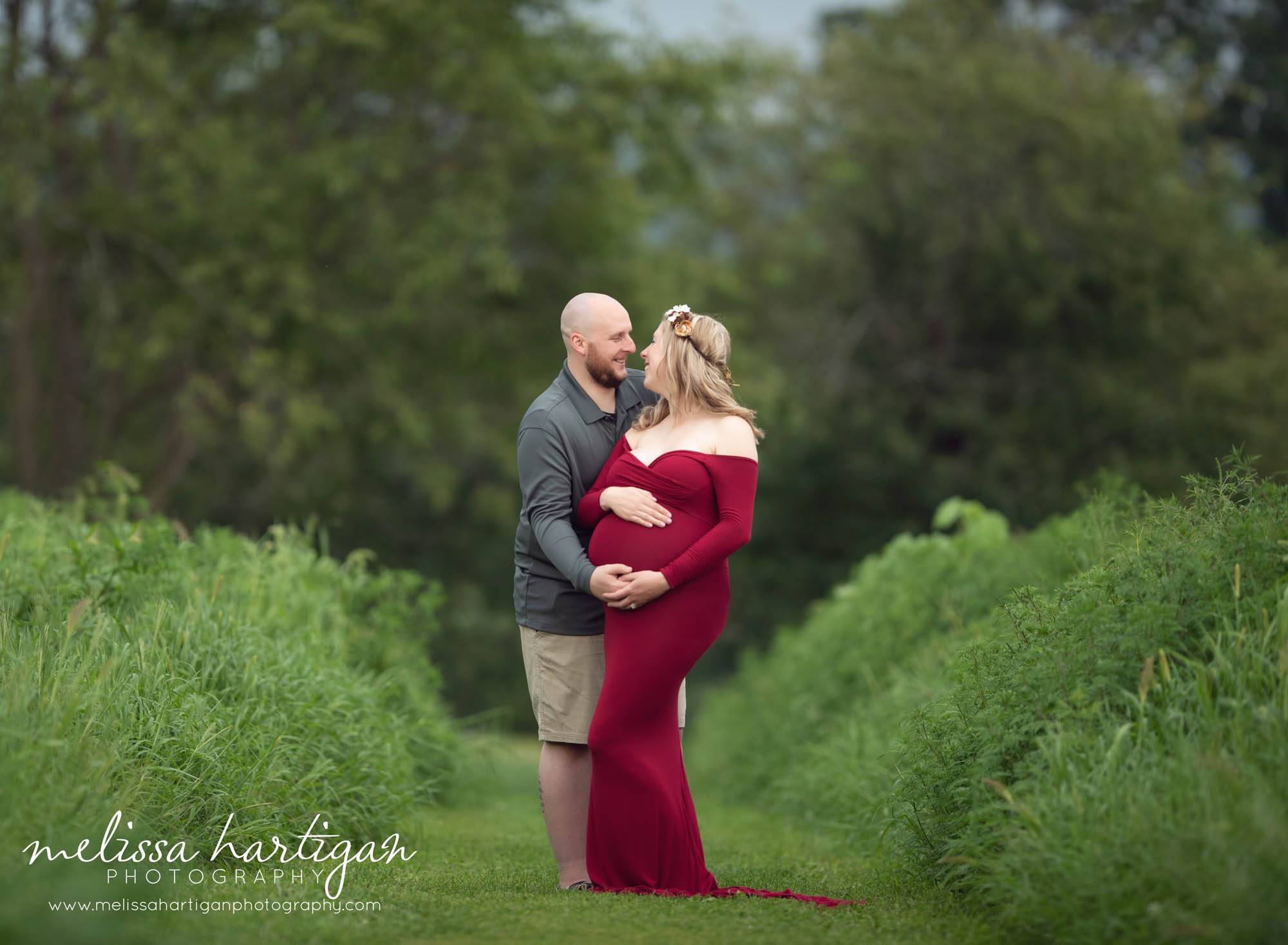 Expectant couple looking at each other and smiling while embracing and holding baby bump Columbia CT maternity photographers
