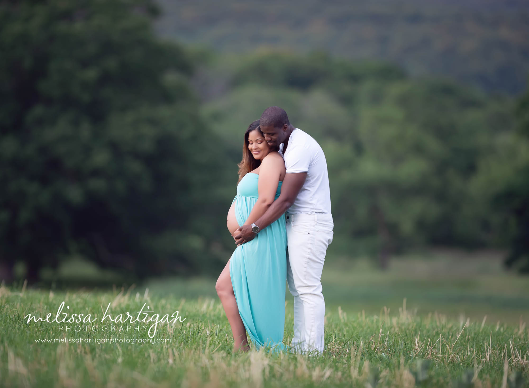 standing maternity couples pose with dad standing behind mom holding baby bump