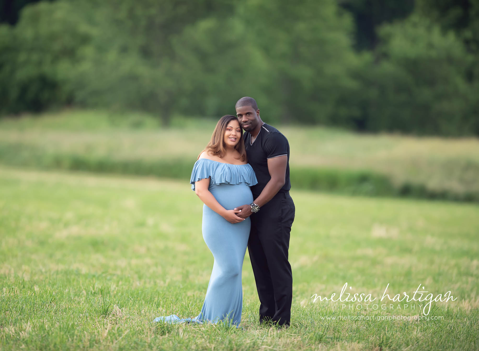 standing maternity couples pose holding baby bump