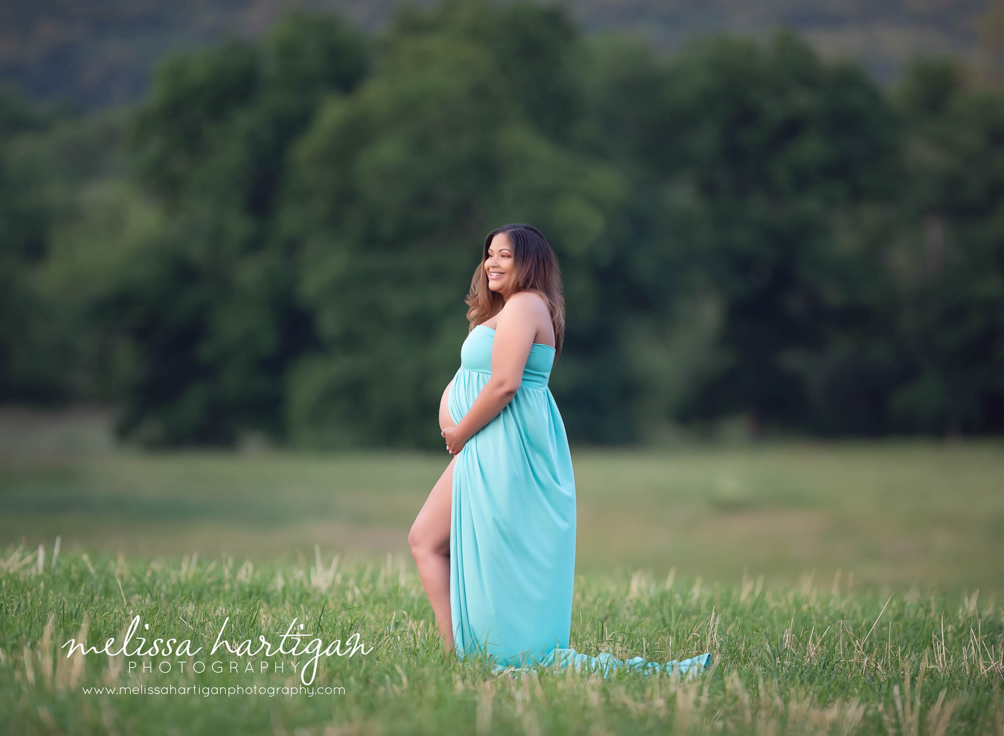 Expectant mom standing maternity pose showing and holding pregnant baby bump looking away from camera CT maternity photography