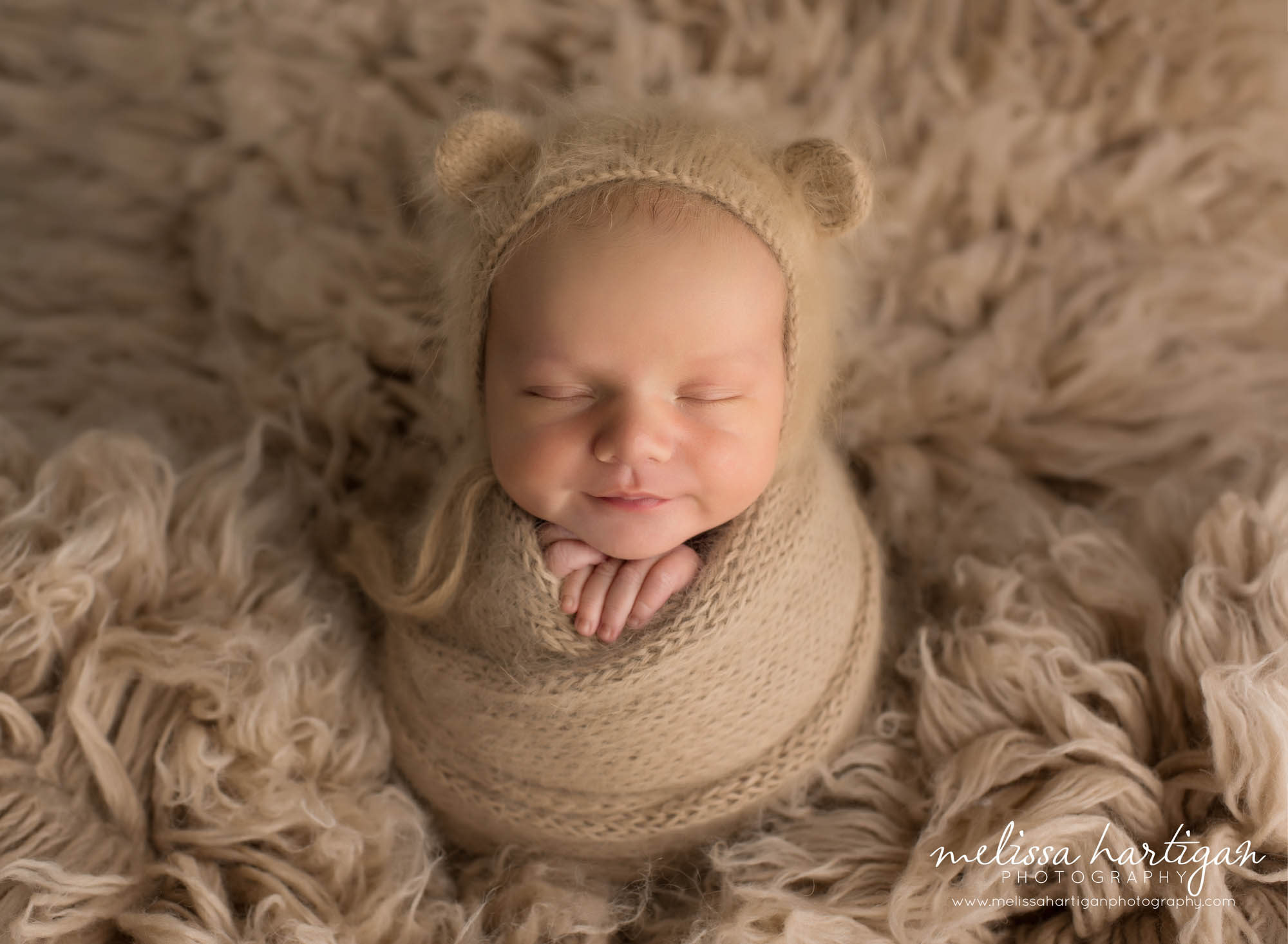 Baby boy wrapped in knitted angora wrap and bear bonnet caramel color