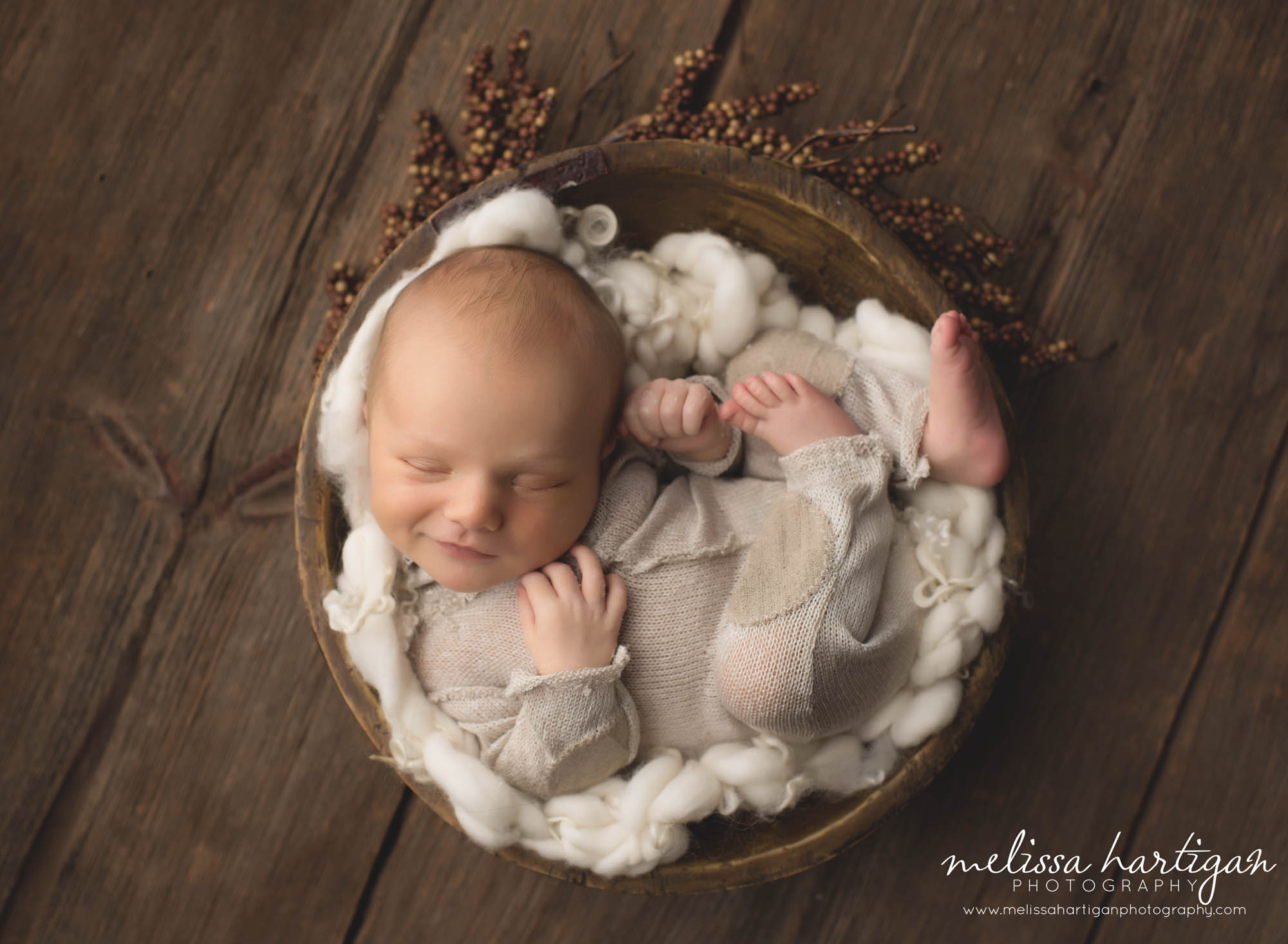 baby boy posed in rustic bowl wearing neutral knitted outfit CT newborn photography