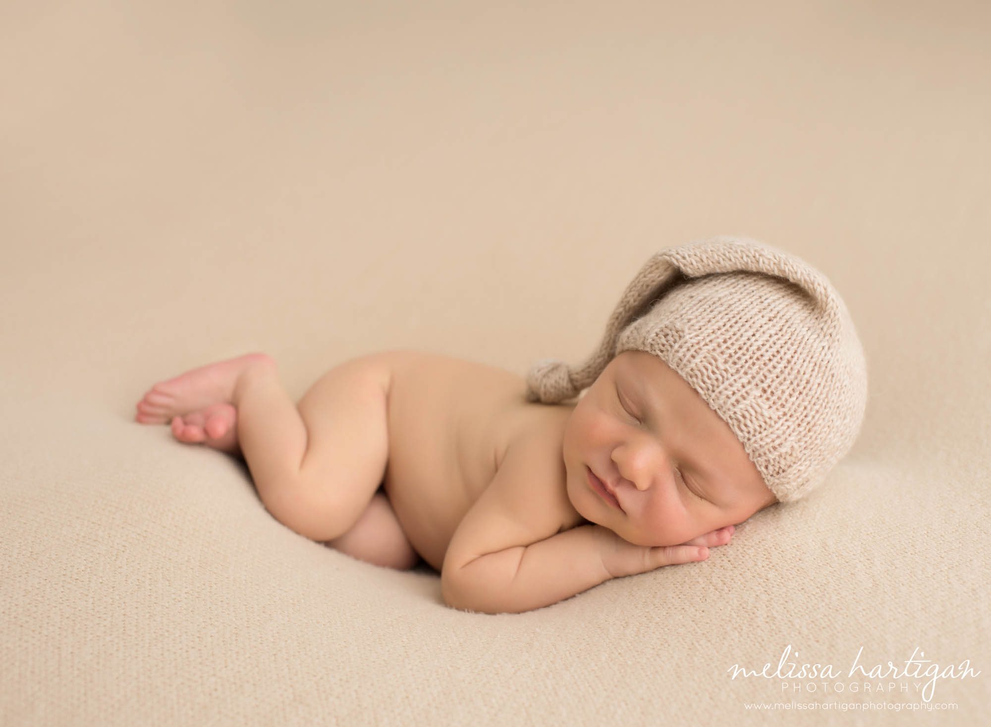 baby boy sleeping on side wearing knitted neutral colored sleepy cap