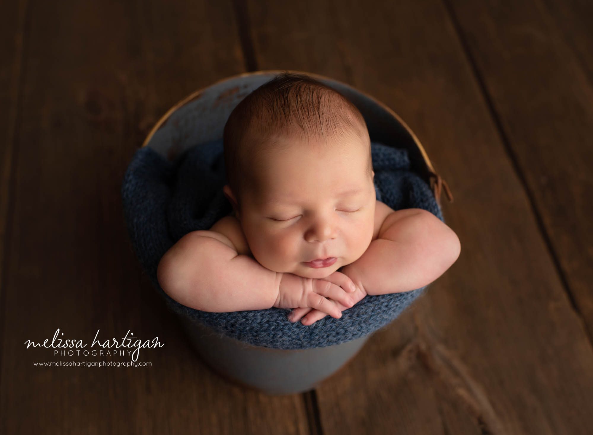 Baby boy posed in bucket with navy blue knitted wrap textured layer
