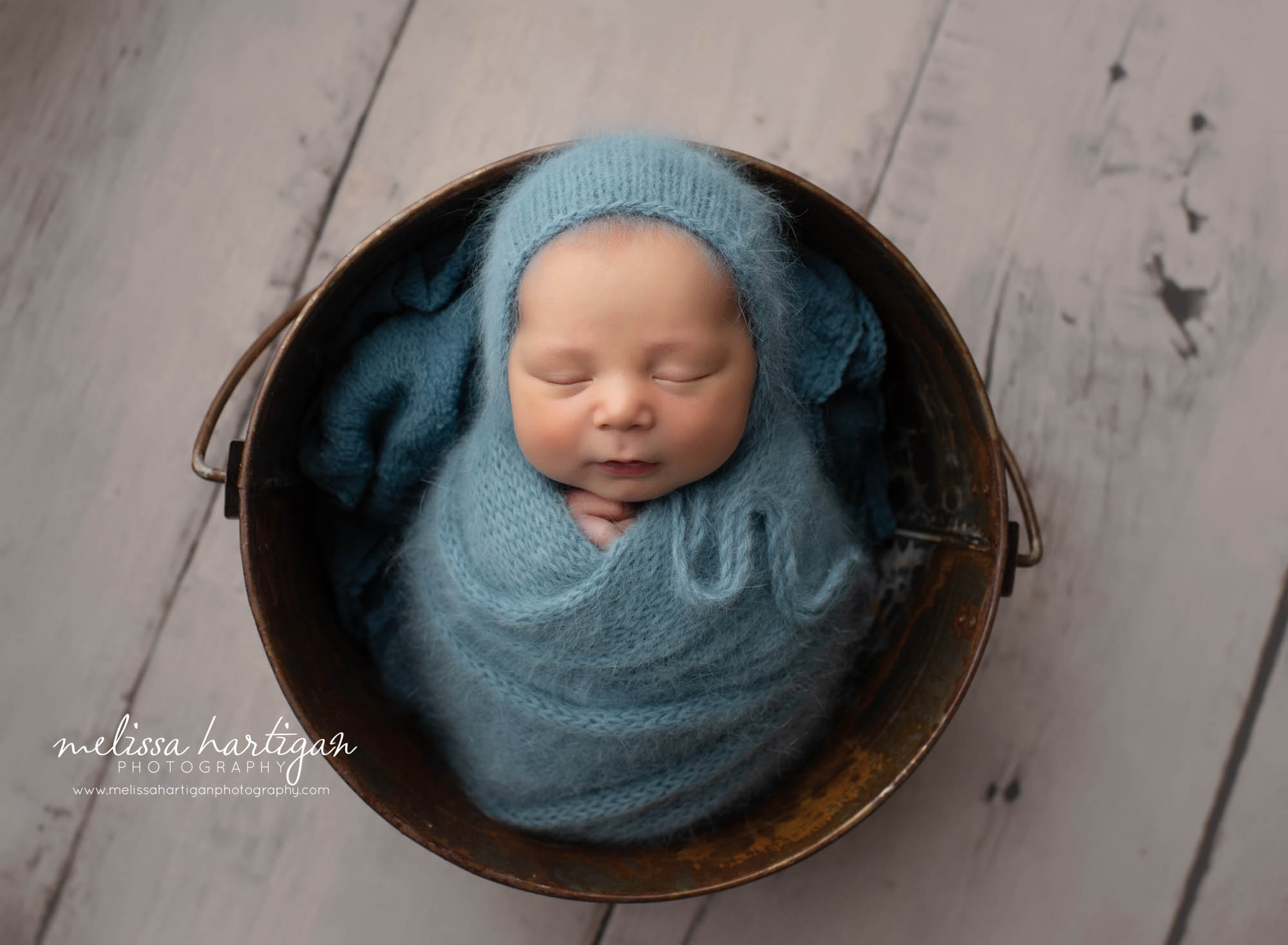 Baby boy sleeping and wrapped in blue with knitted bonnet