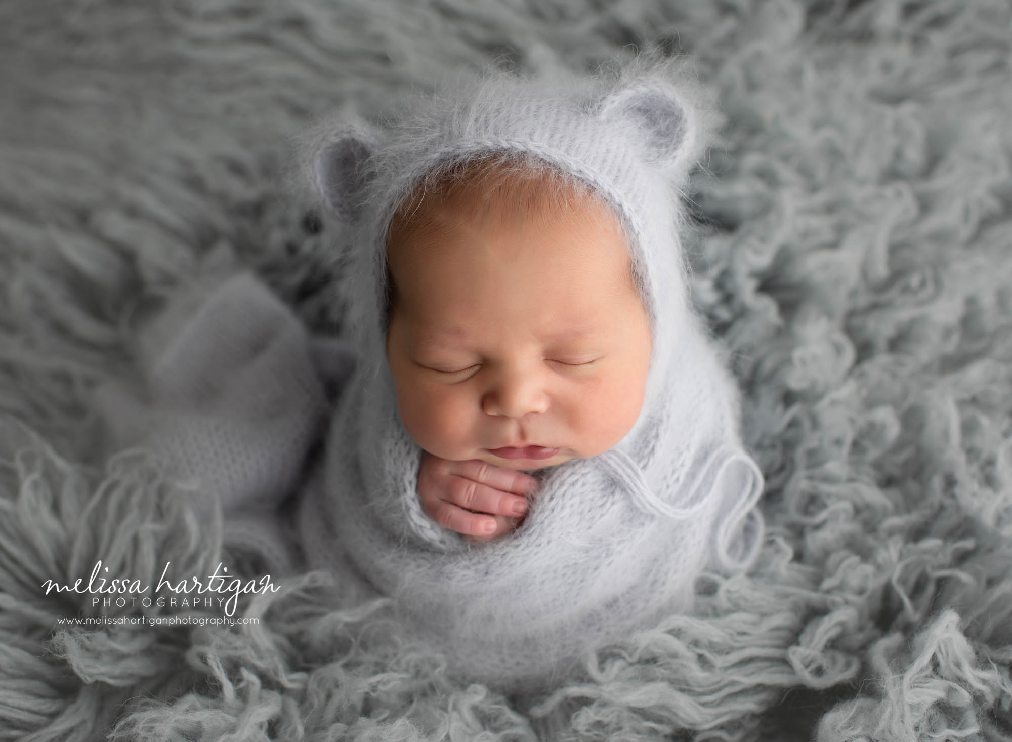 baby boy wrapped in grey flokati with knitted wrap and angora bear bonnet Columbia CT Newborn Photographer