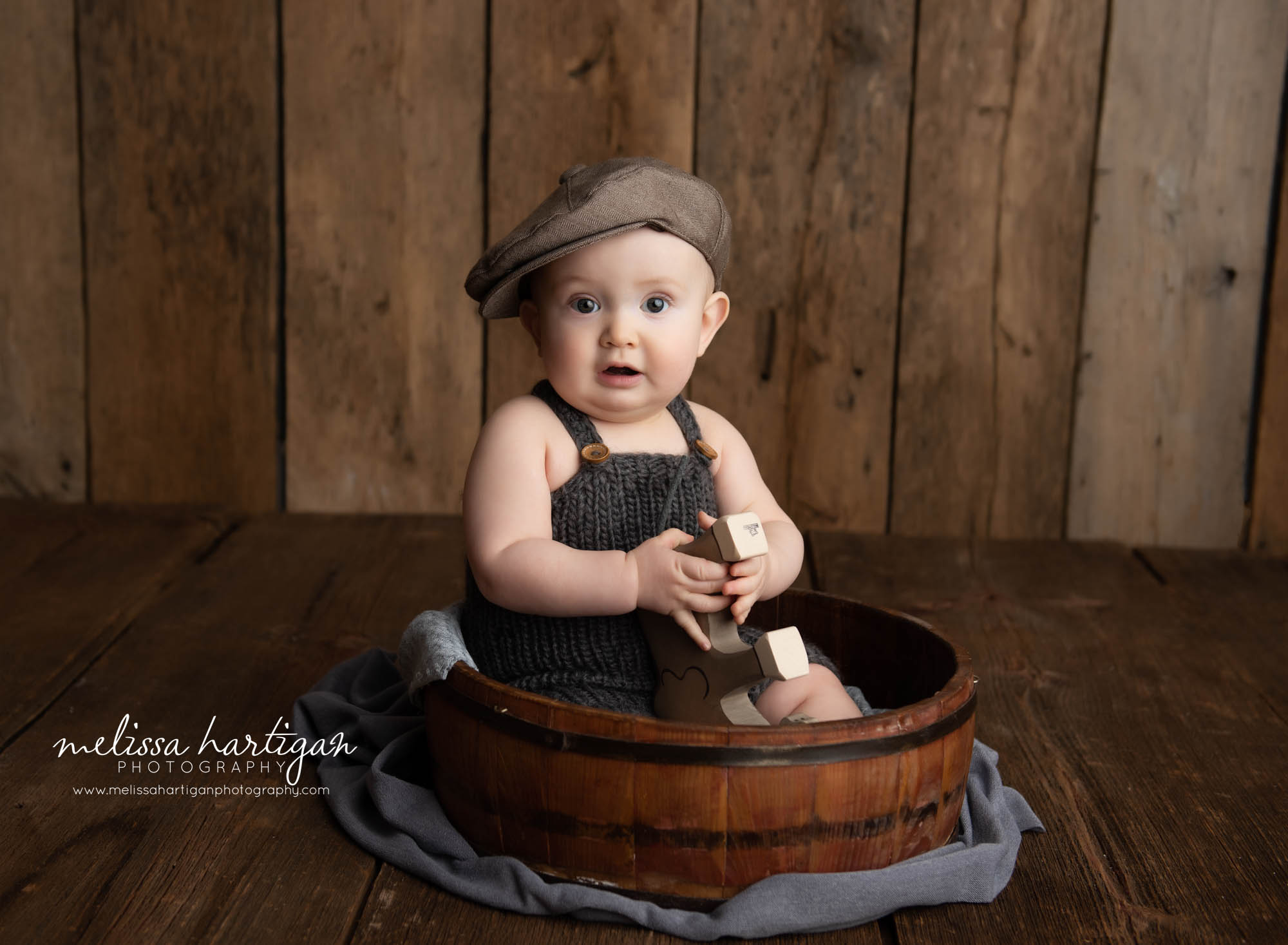 baby boy sitting in rustic bowl prop with hat