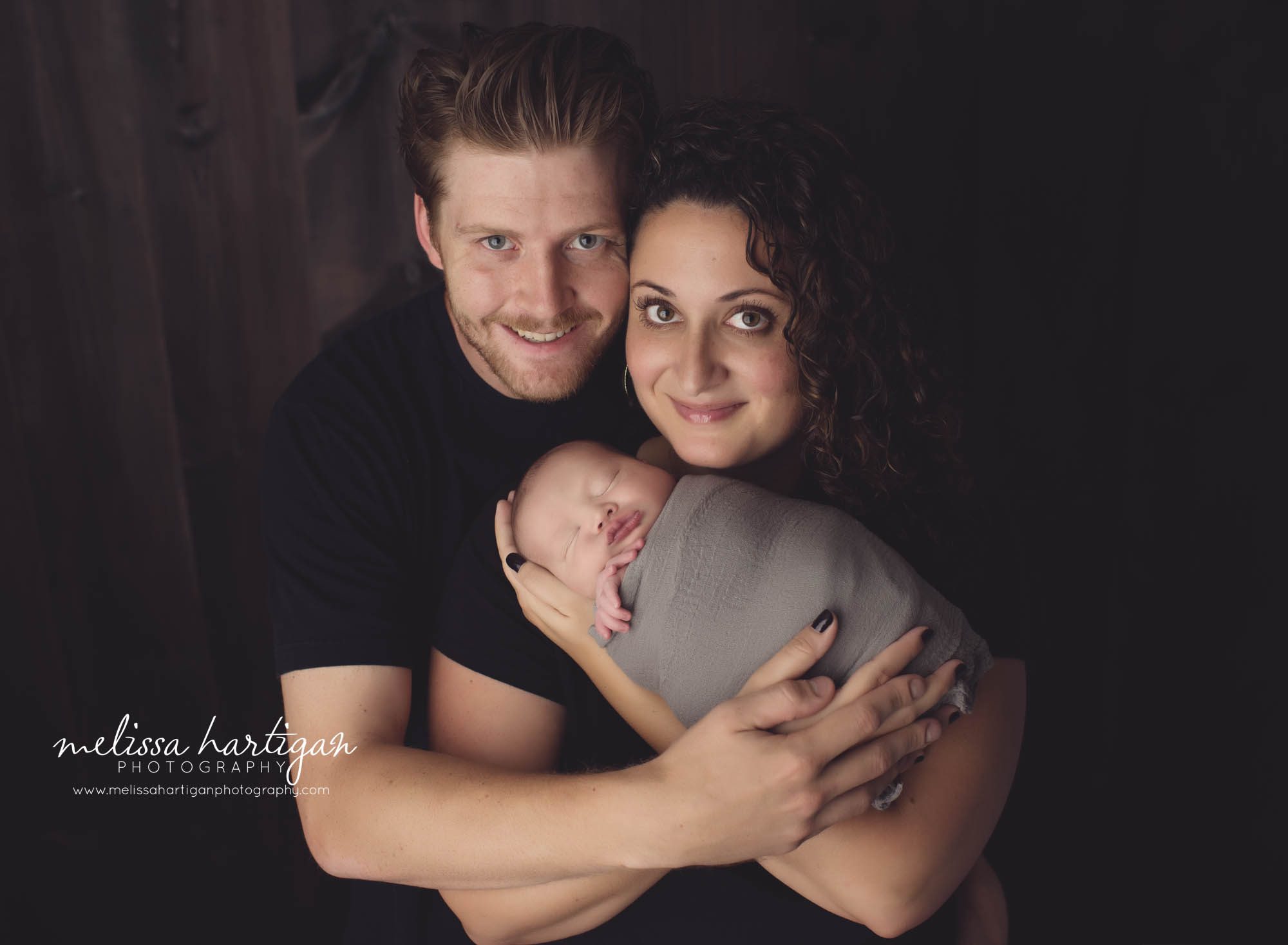 Family photo with newborn baby boy wrapped with mom and dad holding him