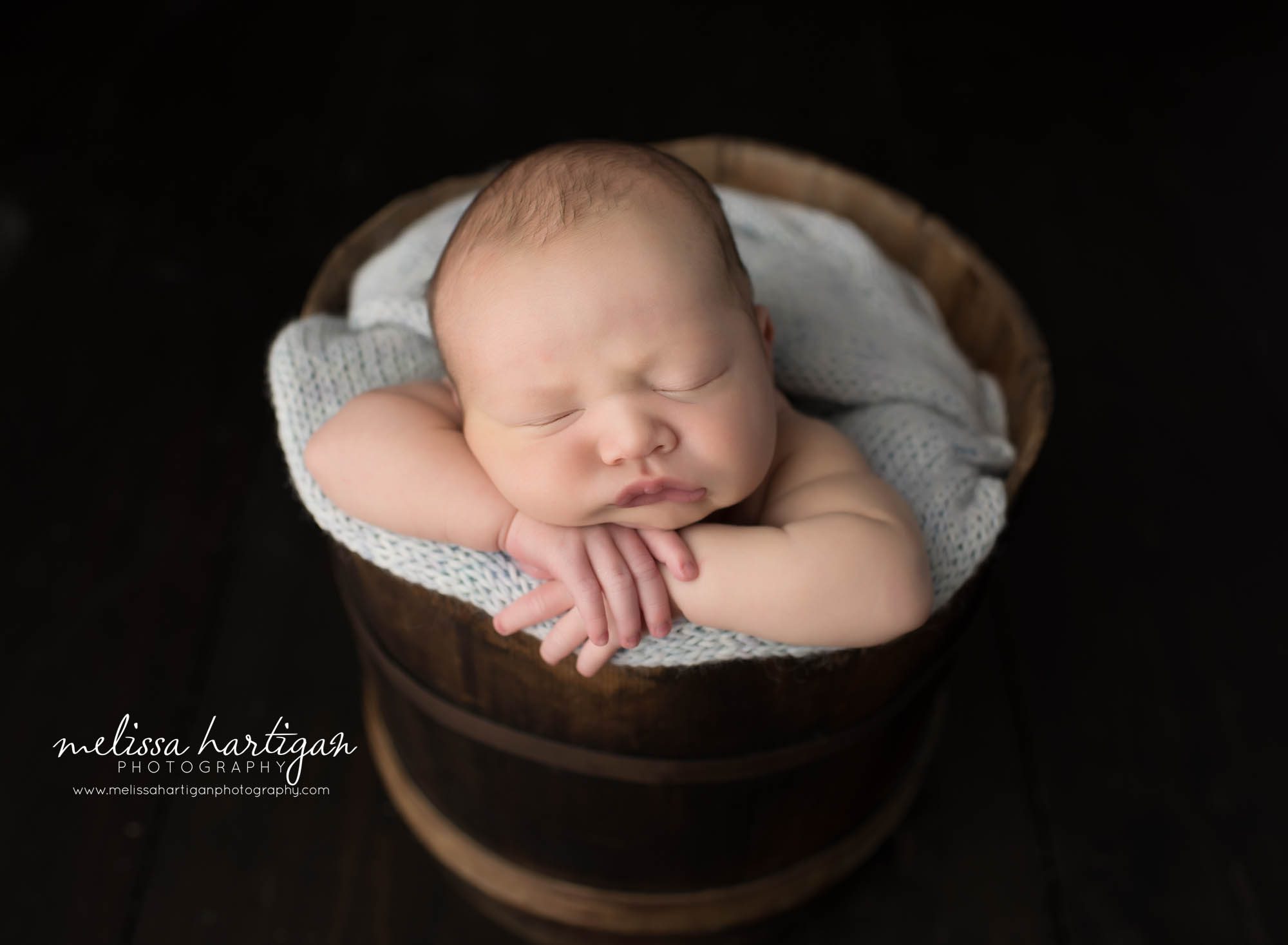 baby boy posed in rustic wooden bucket with light blue-grey knitted wrap
