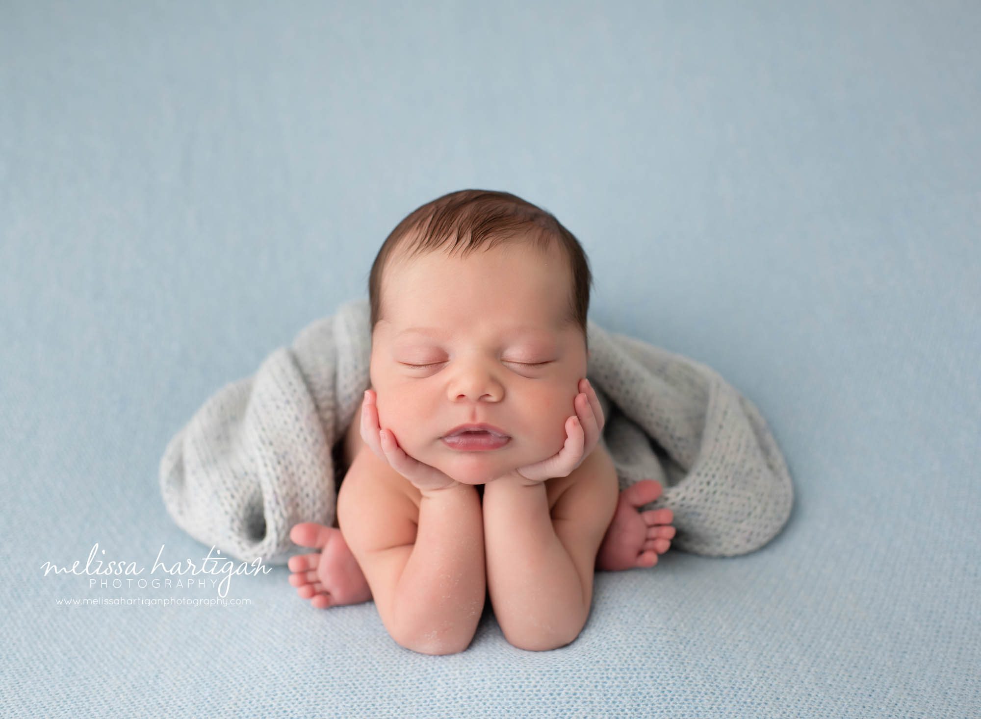 Baby boy posed on light blue backdrop in froggy pose with knitted layering texture newborn Photographer Storrs CT