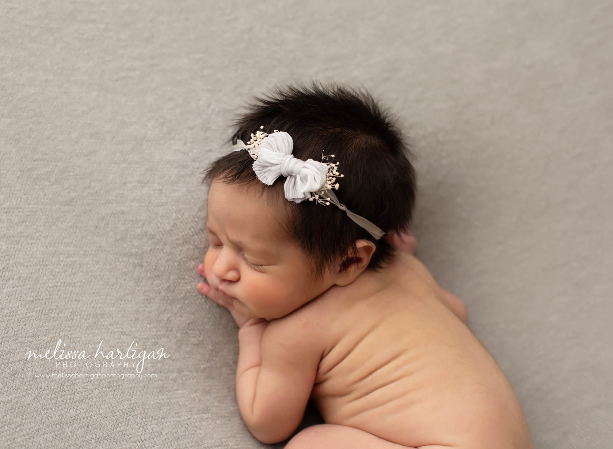 Baby girl posed on tummy wearing silver bow headband