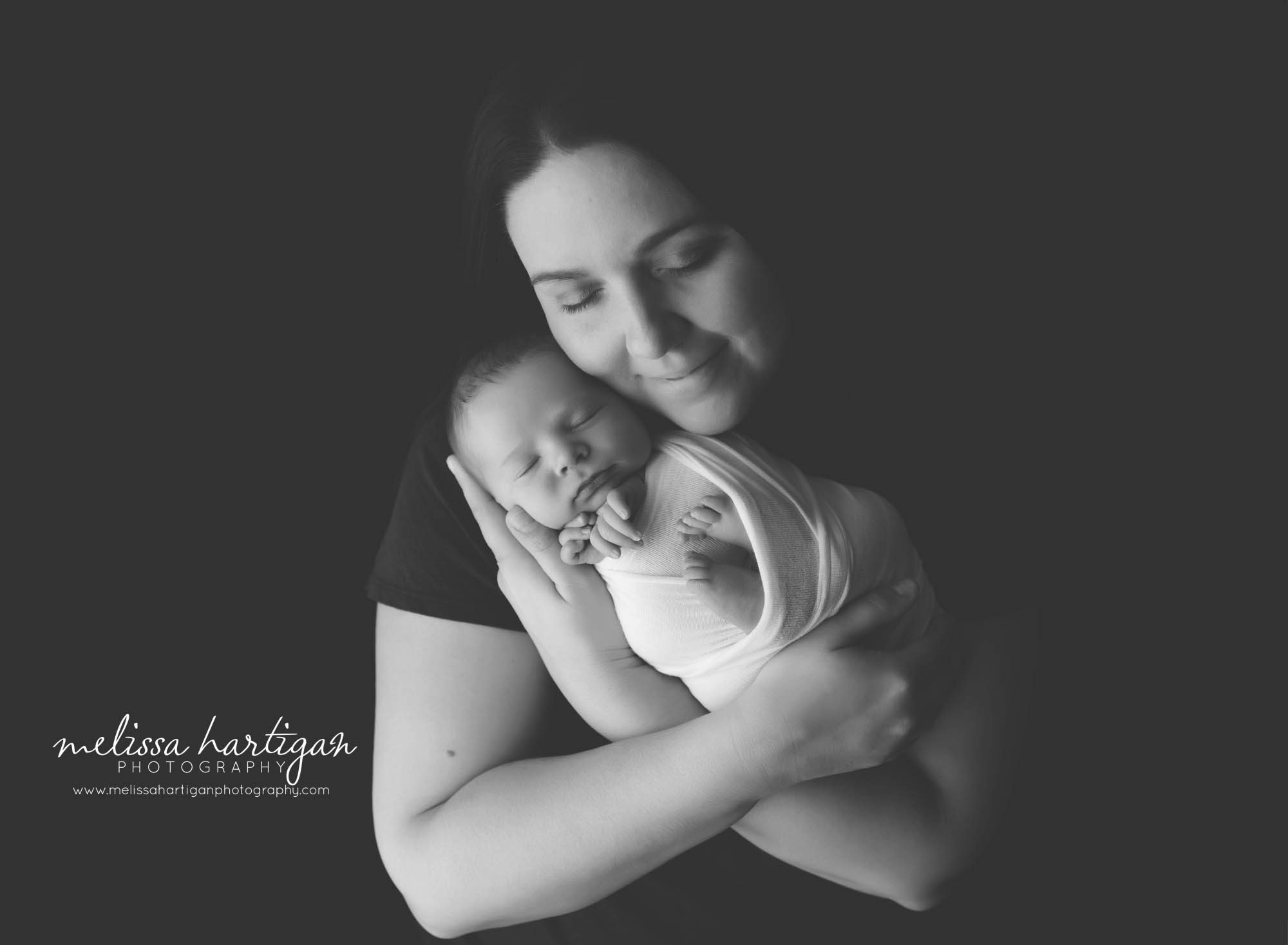 mom holding newborn baby is studio newborn photography session