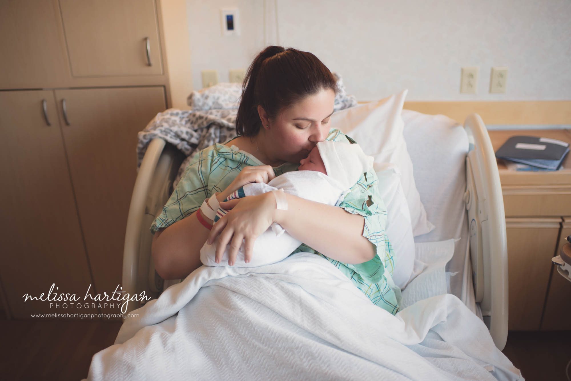mom and baby boy snuggling in hospital bed