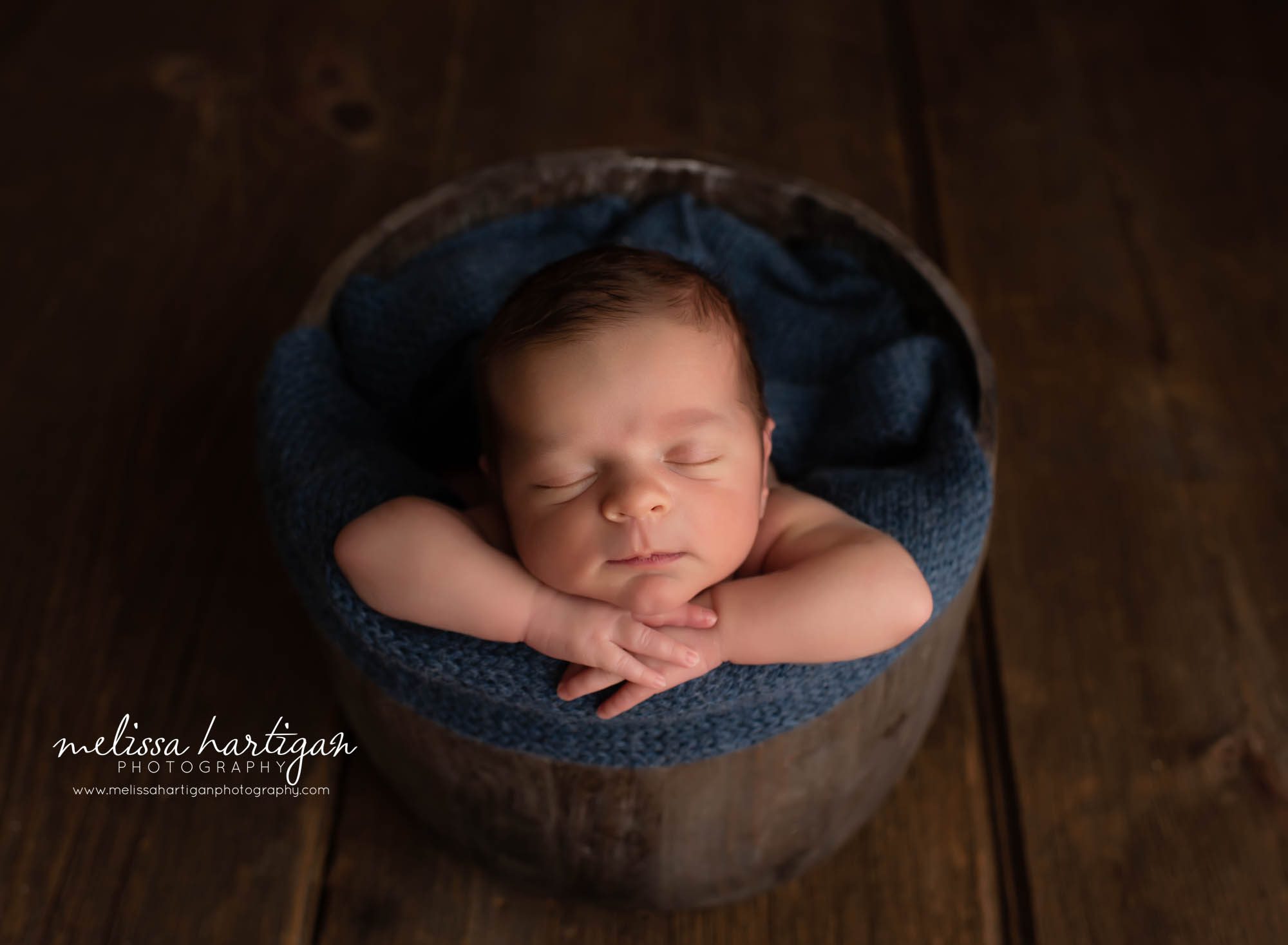 baby posed in wooden rustic bucket with navy blue knitted wrap Coventry CT Newborn Photographer