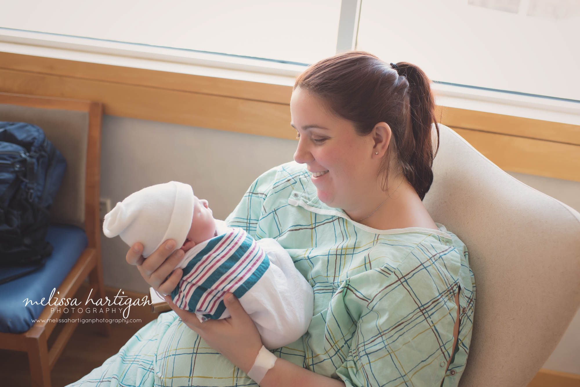 mom holding newborn baby boy wrapped in hospital blanket