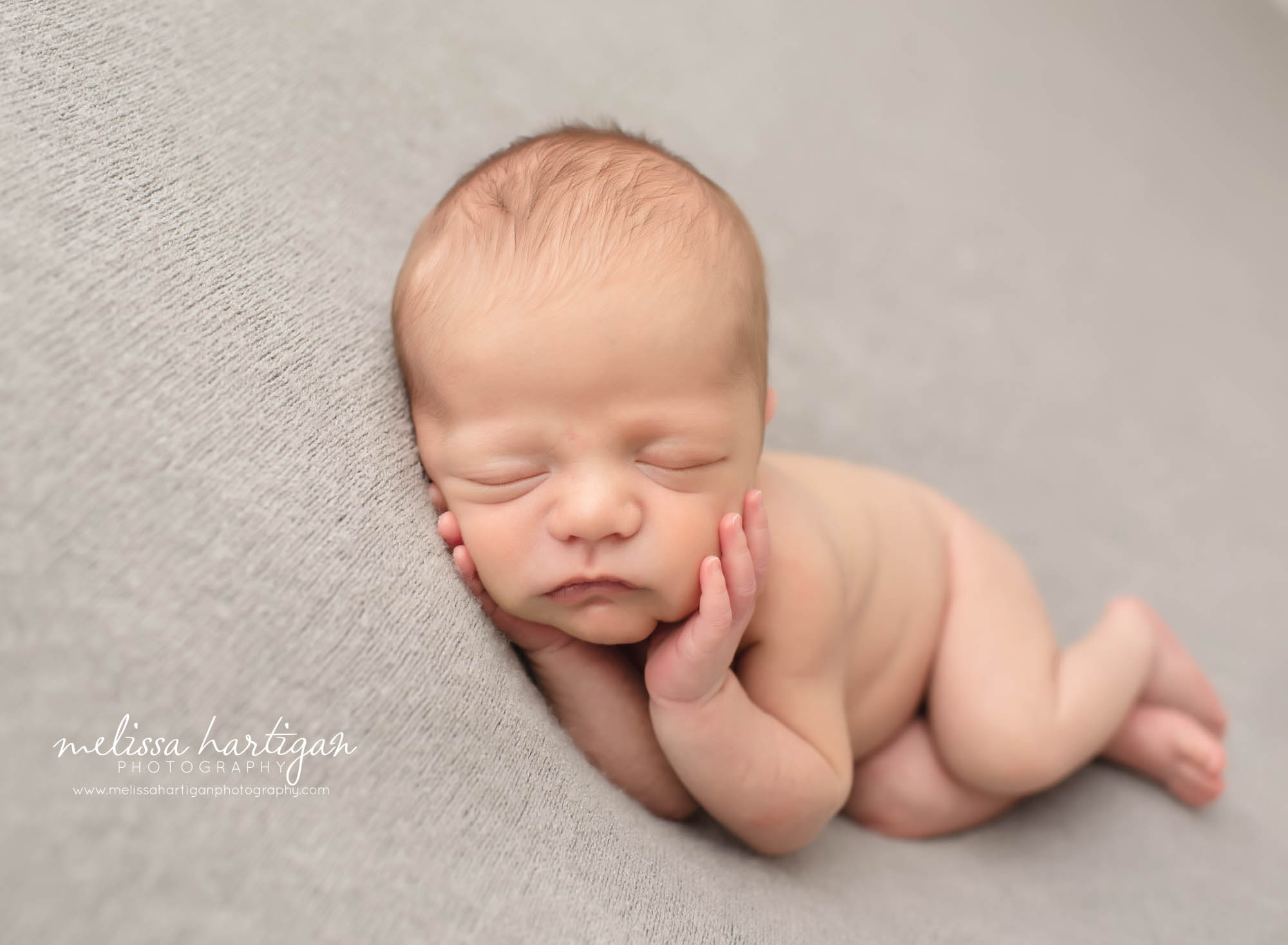 Baby boy laying on side in light grey blanket backdrop
