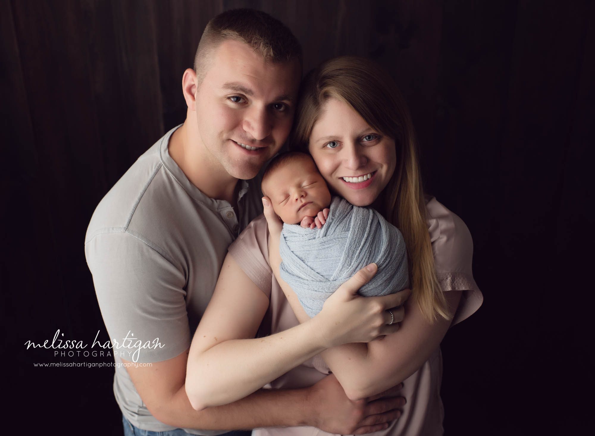 Newborn baby boy wrapped in blue wrap with mom holding him and dad holding mom newborn baby and family photo Tolland County newborn photographer