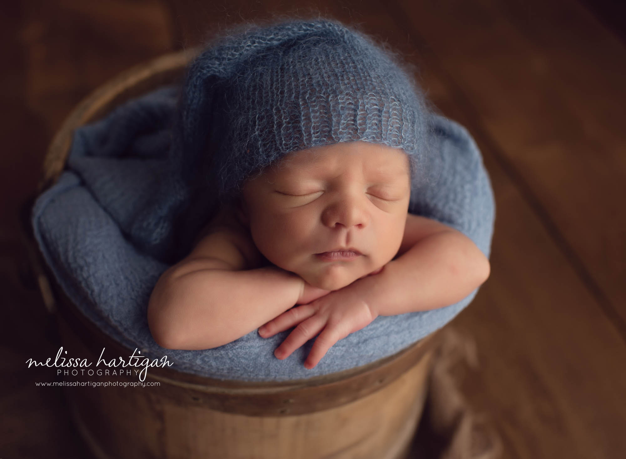 Baby boy posed newborn photography pictures posed in rustic bucket with blue knitted sleepy cap