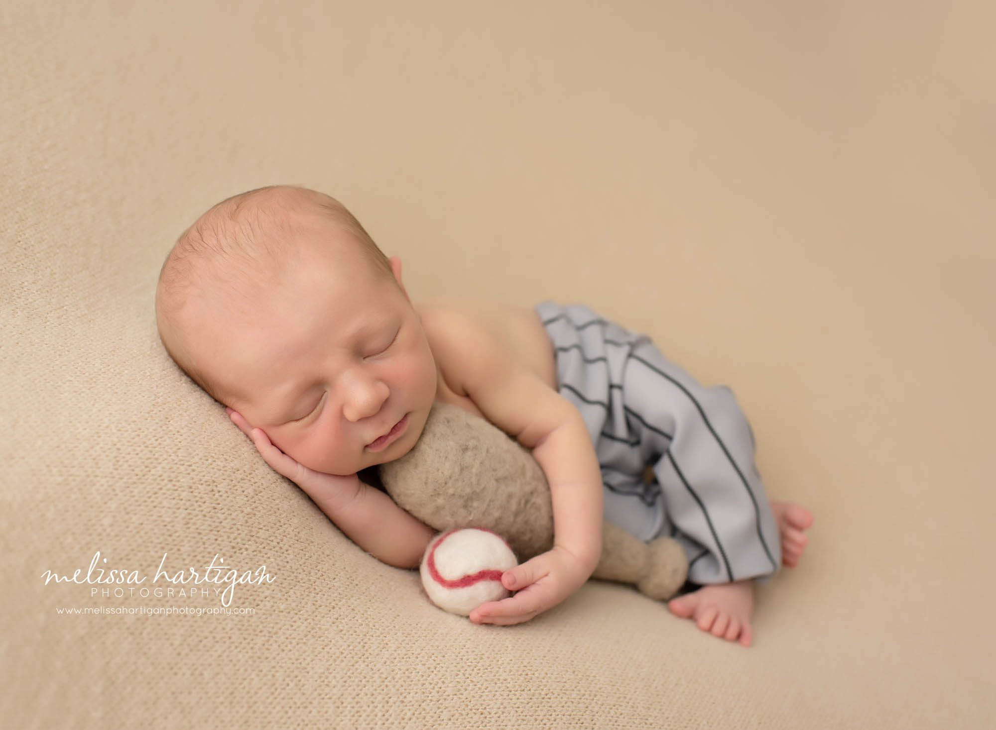 baby boy sleeping on side posed with baseball bat and baseball Ct newborn photographer
