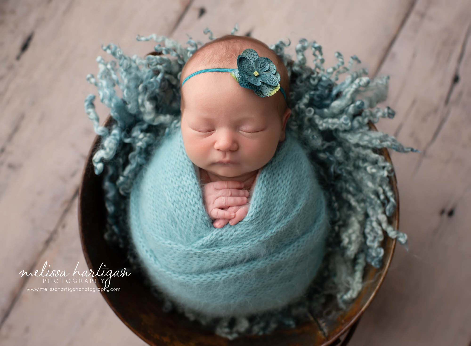 baby girl posed in bucket on her back with teal colored knitted wrap and teal colored curly layer CT baby photography