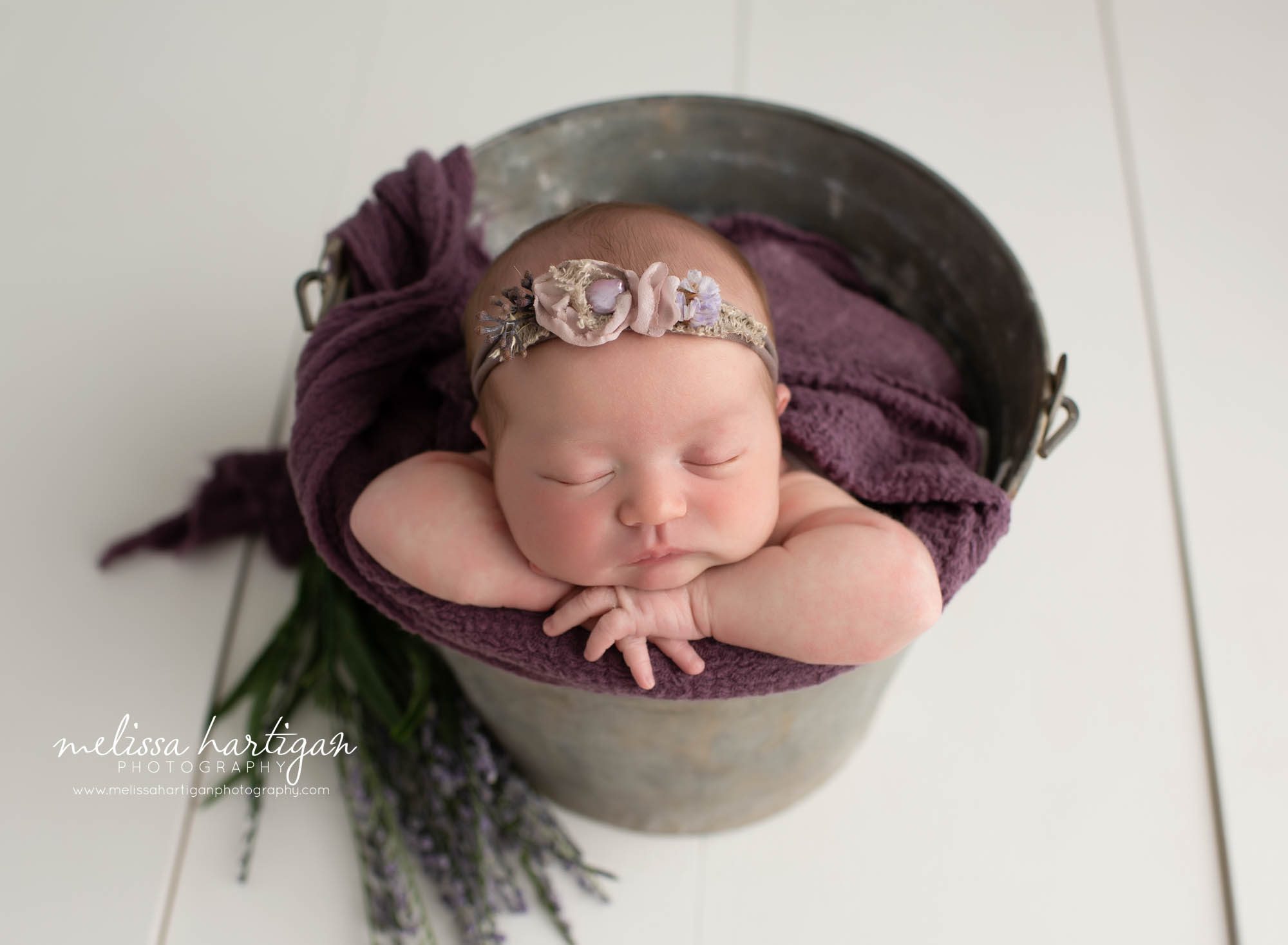 Baby girl posed in metal bucket with floral headband and stems of lavender