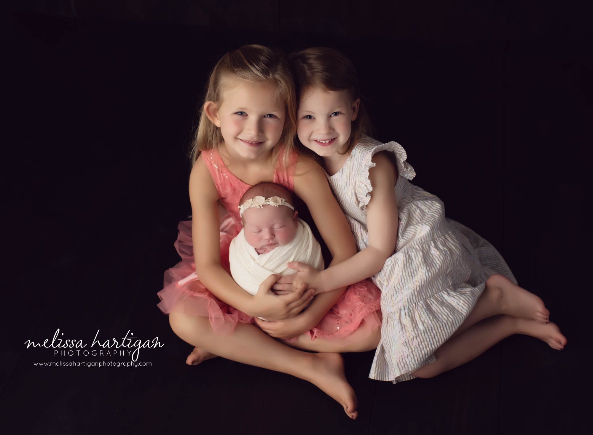 newborn baby girl being held by her sisters studiop sibling photo pose
