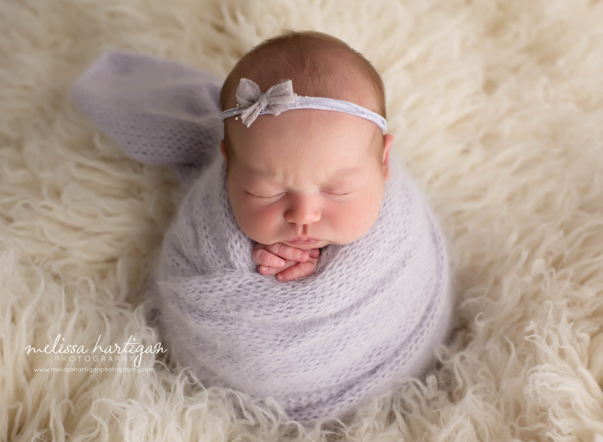 Baby girl wrapped in light purple knitted wrap with liliac colored headband