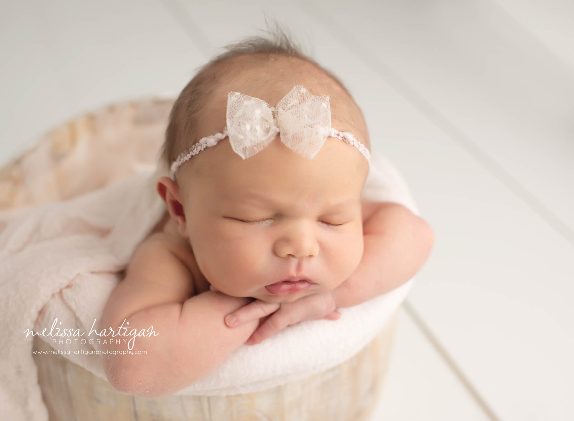 Baby girl in bucket with bow headband and light pink