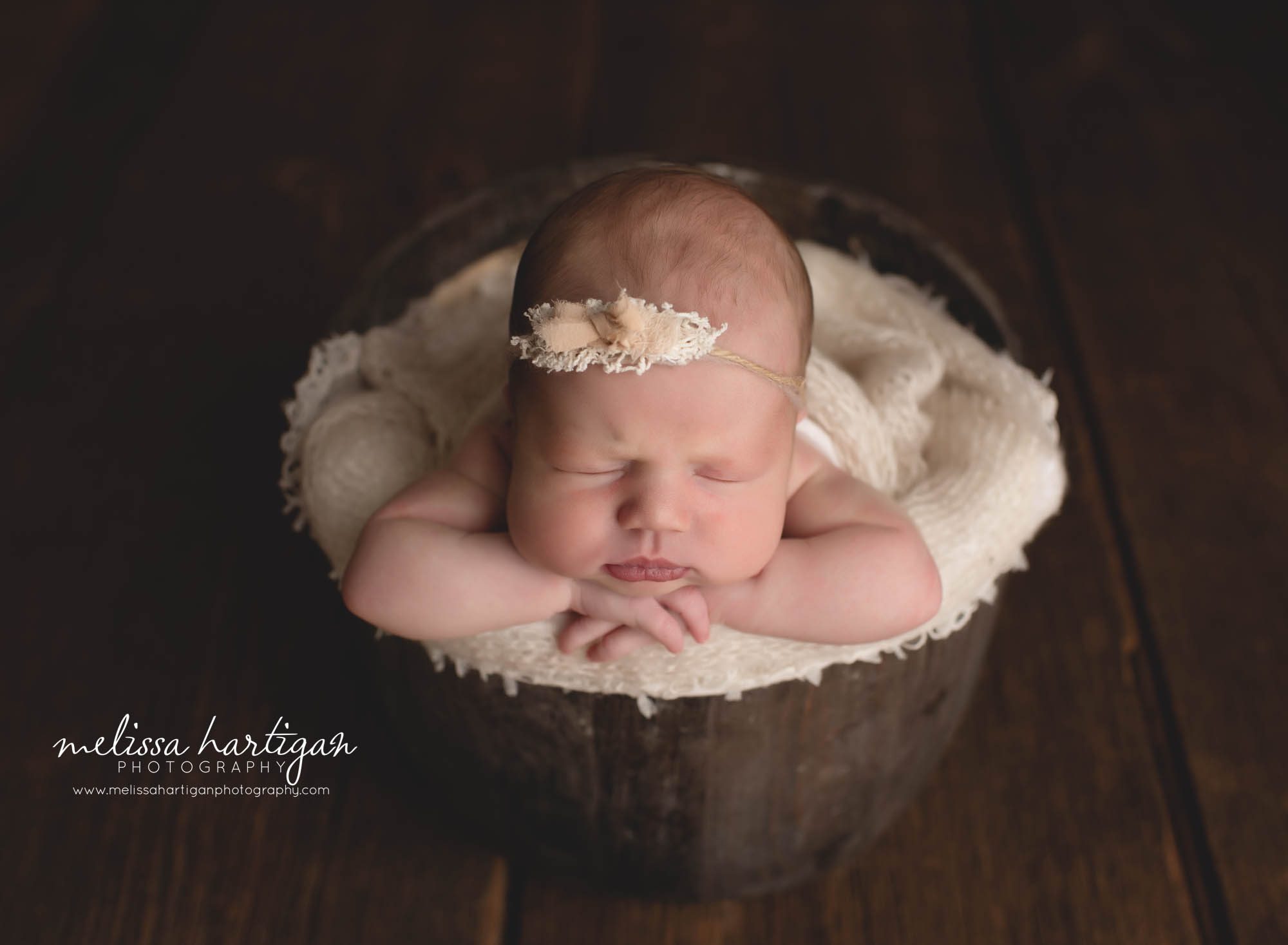 baby girl posed in brown wooden bucket with cream and floral tie back CT newborn photography