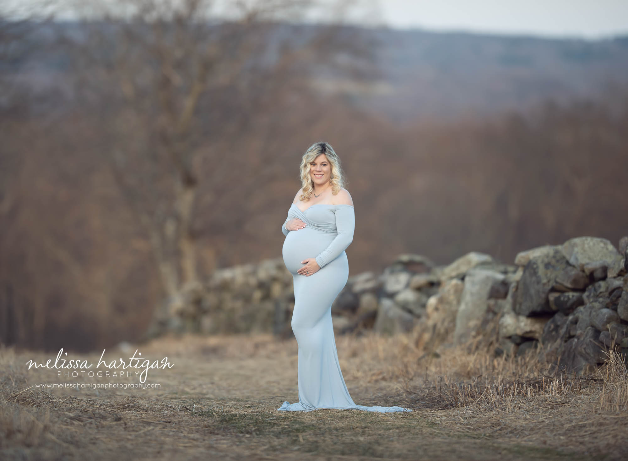 Expectant mom wearing long fitted gown maternity standing pose