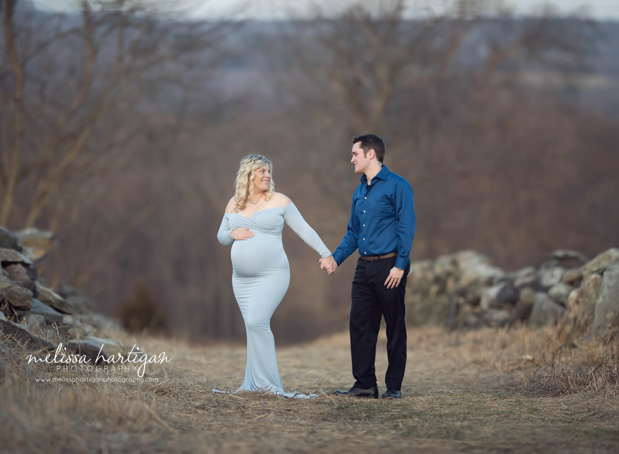Couple holding hands walking with mom holding her pregnant baby belly