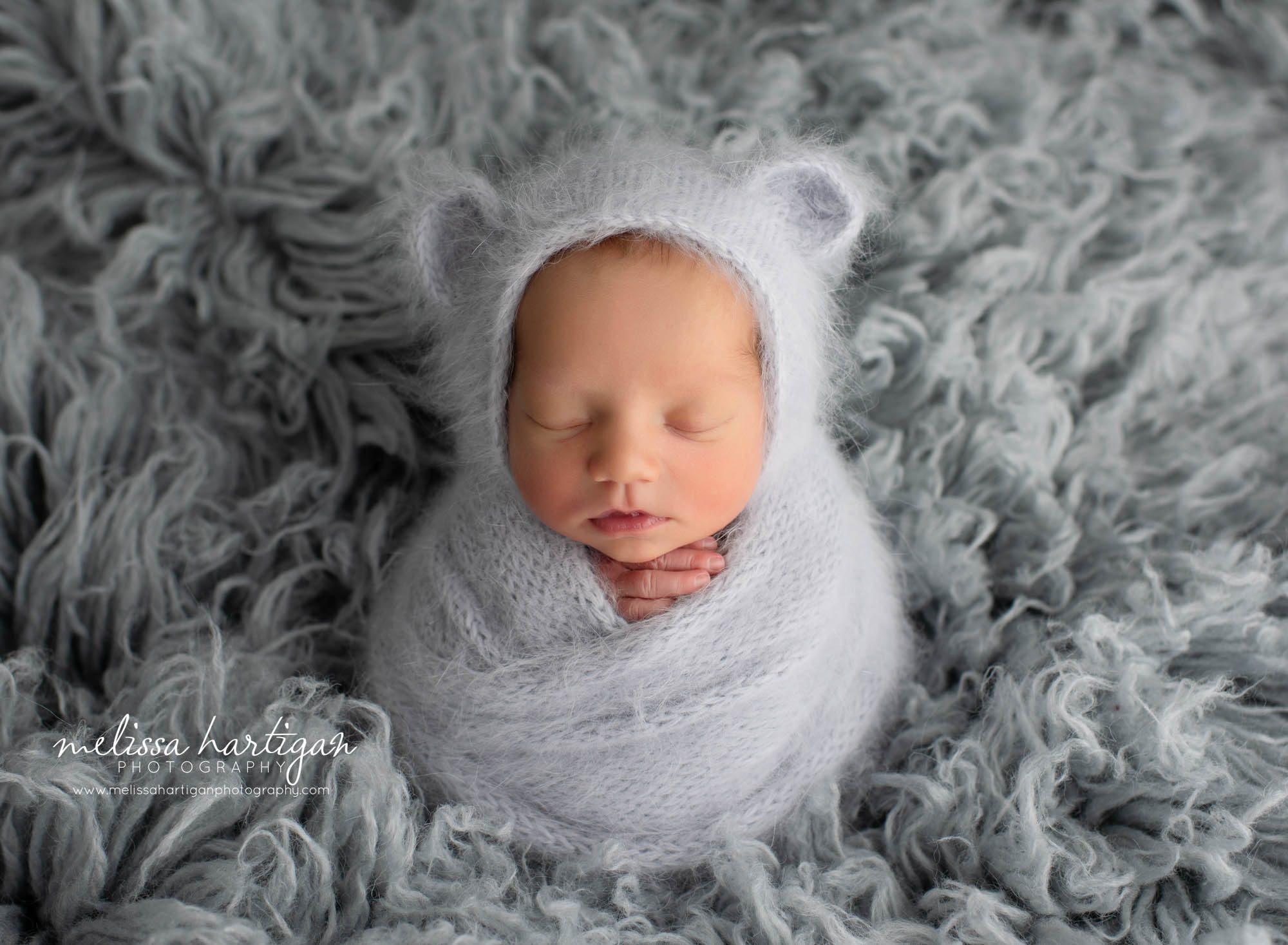 Baby boy wrapped in knitted light grey wrap and matching bear bonnet Connecticut Newborn photography