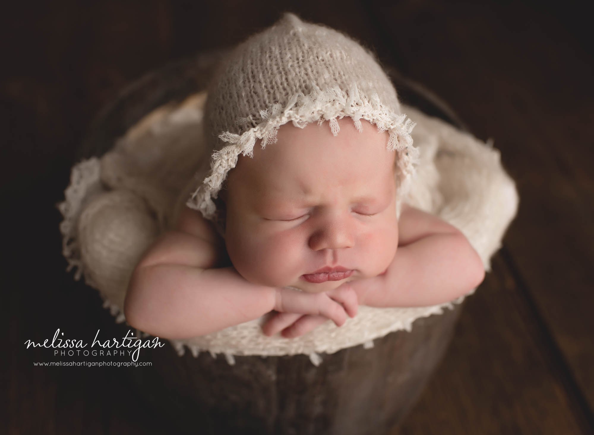 Baby girl posed in bucket wearing knitted bonnet Stafford CT baby photography