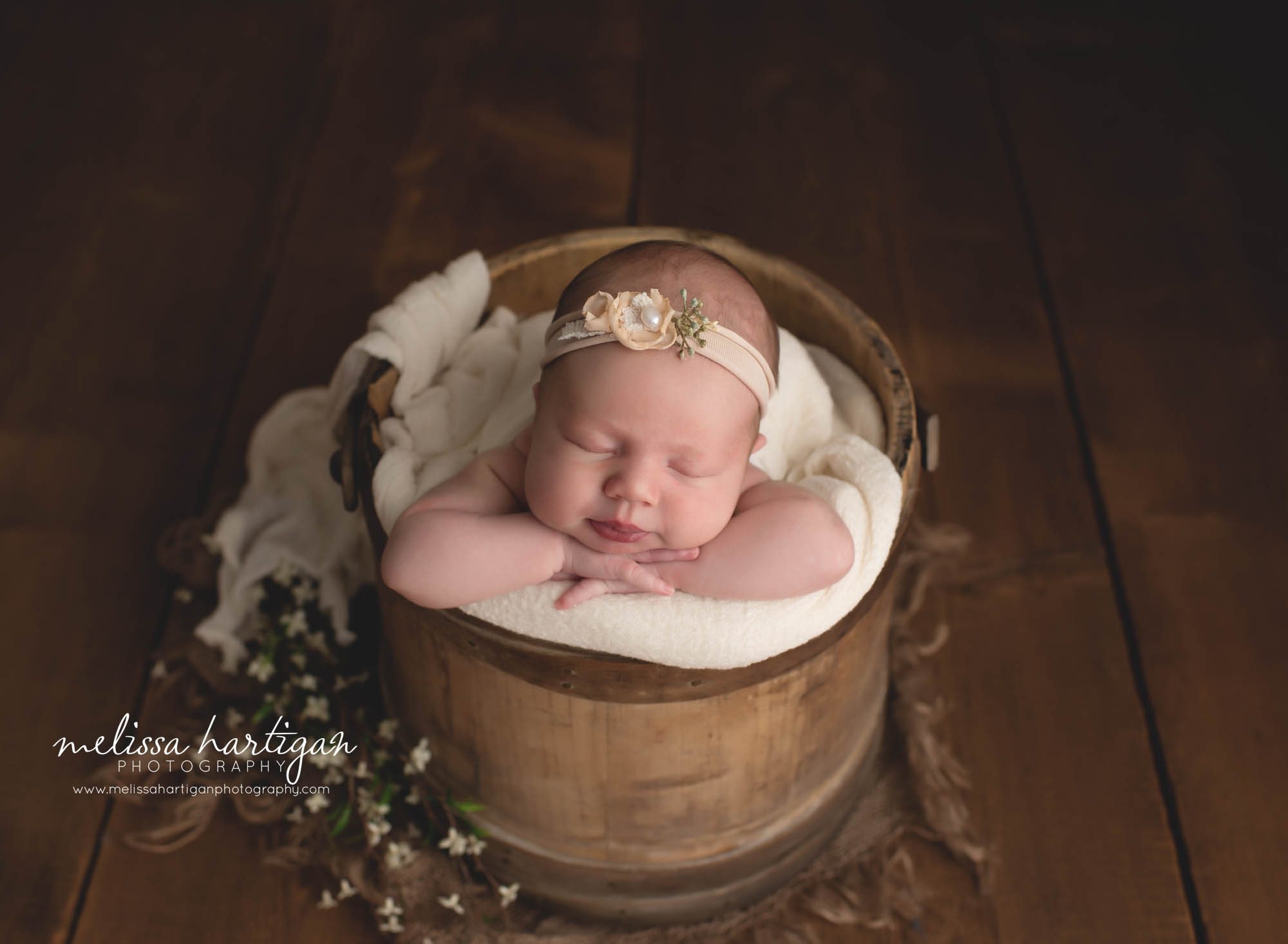 baby girl posed in rustic wooden bucket with head on hands