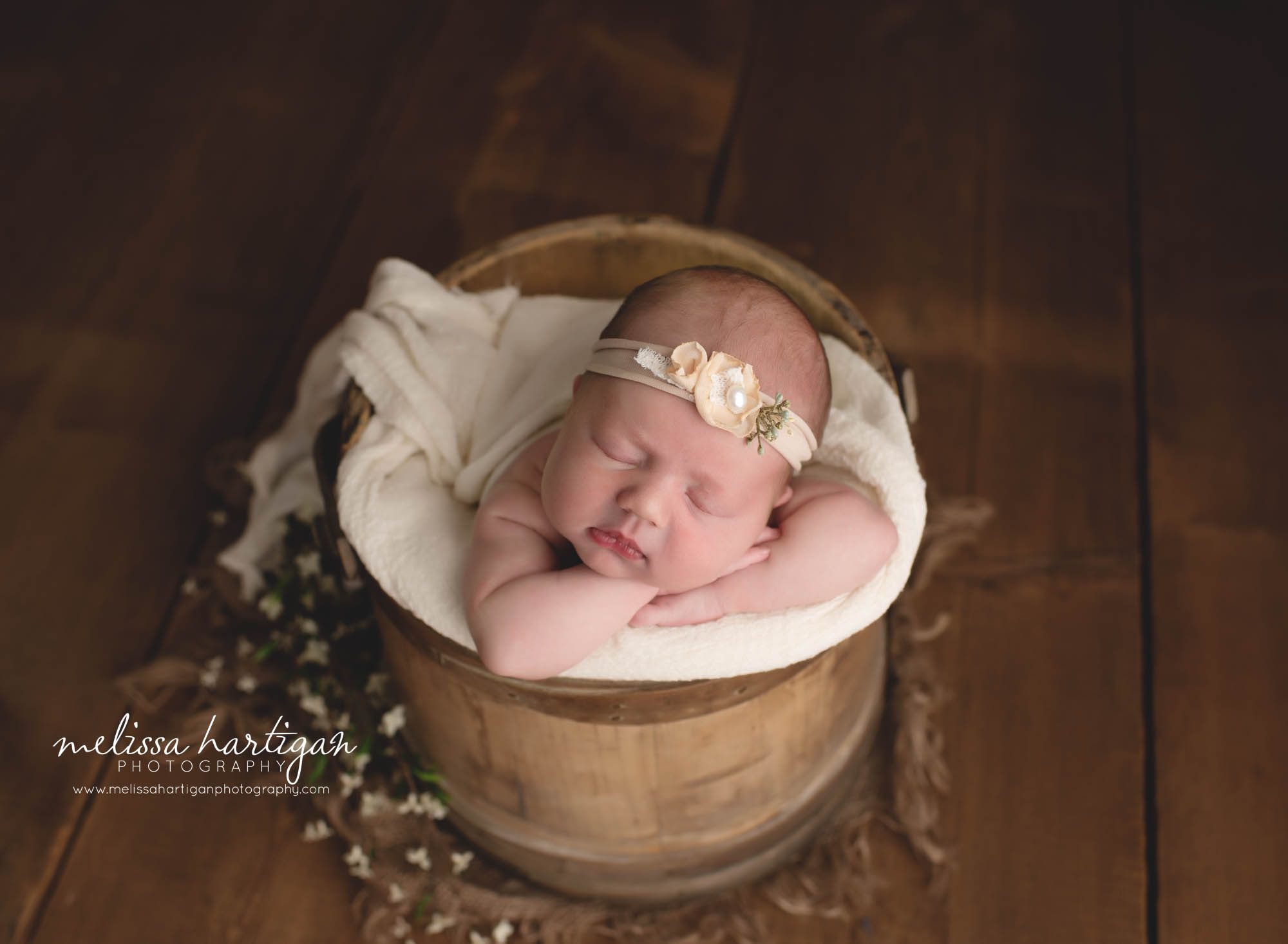 Baby girl posed in bucket with cream and peach floral headband