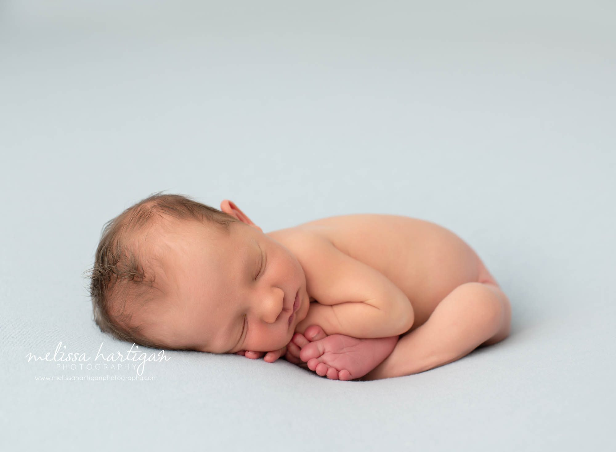 Newborn baby boy taco pose on light blue backdrop studio newborn photography session