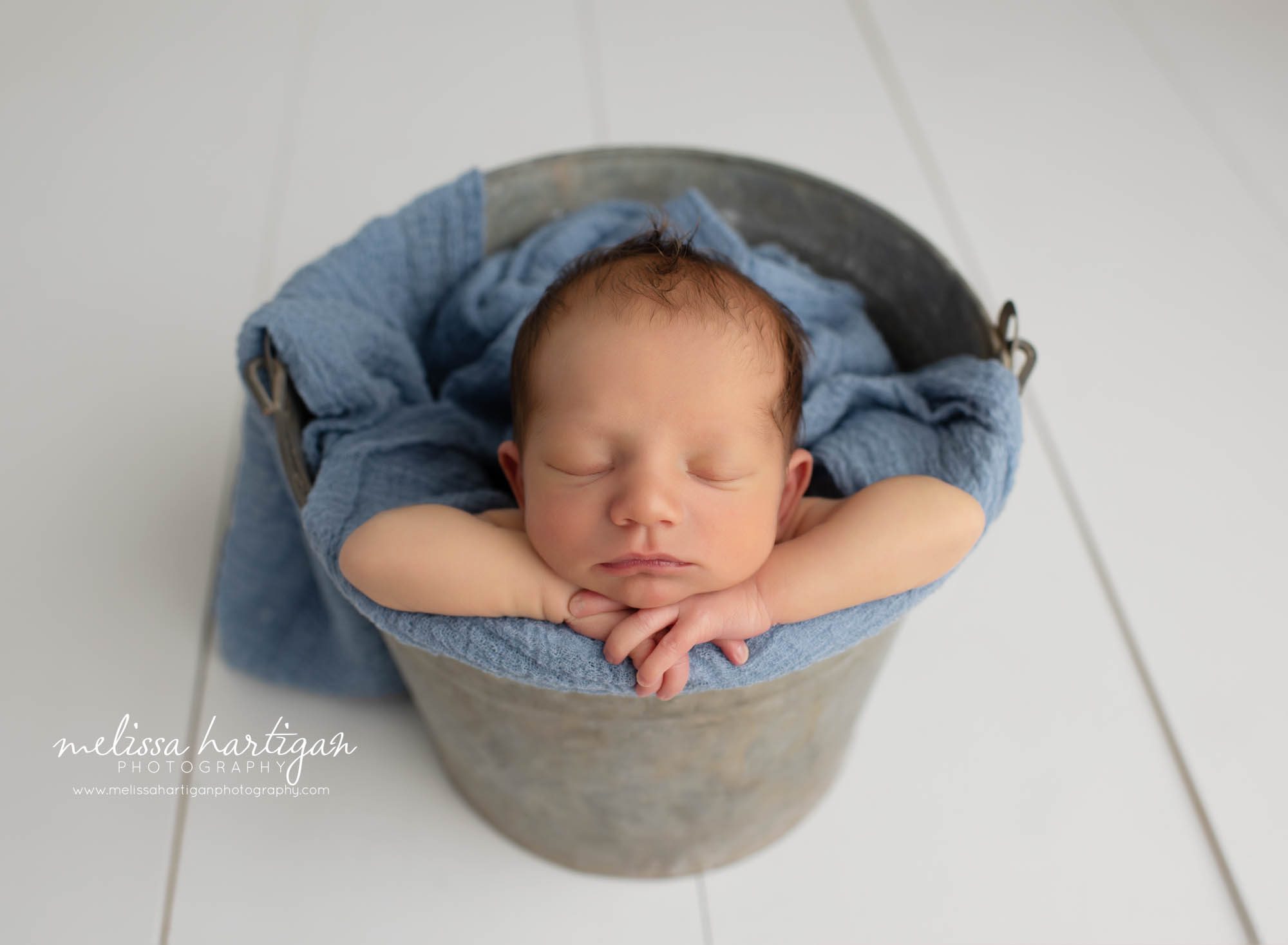 baby boy posed in metal bucket with head on hands