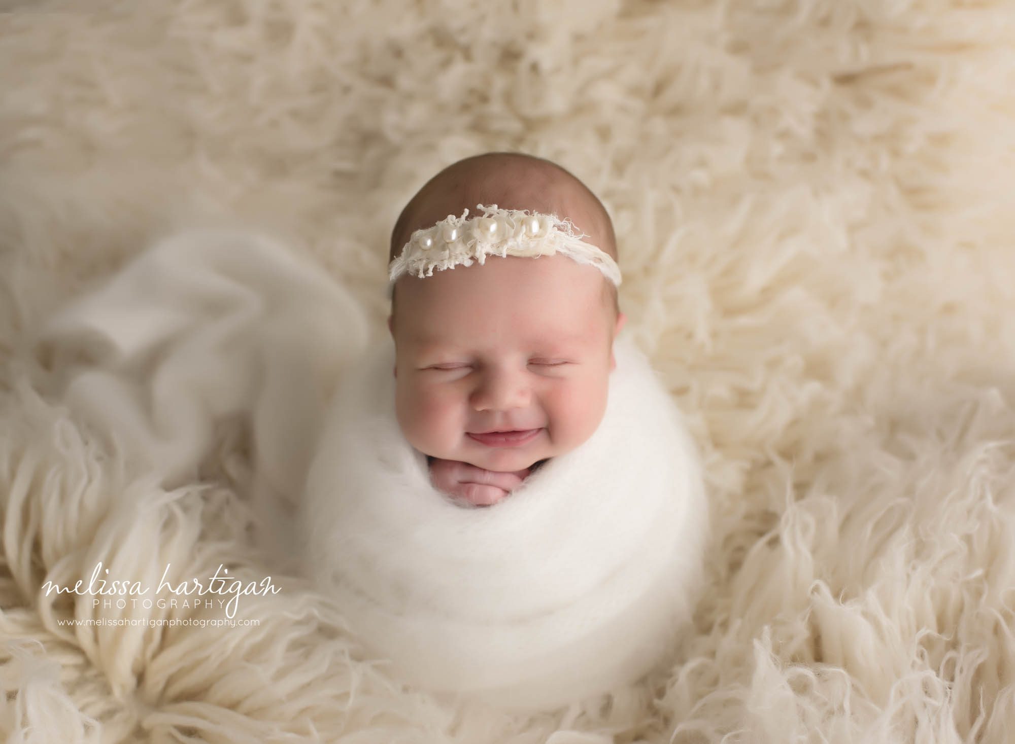 Baby girl wrapped in white knitted wrap on cream flokati CT newborn photographer