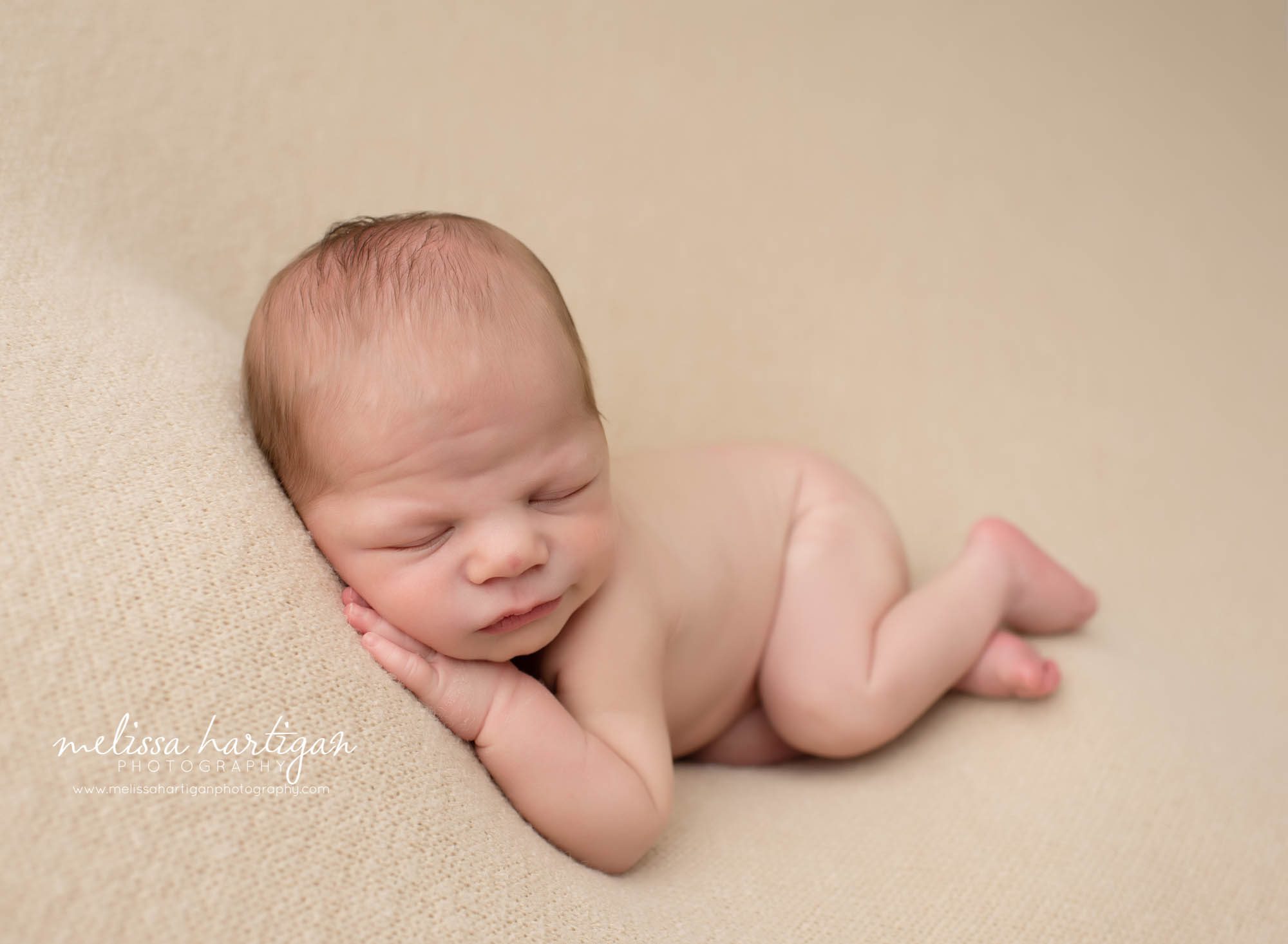 newborn baby boy sleeping on side on neutral colored backdropo newborn photography