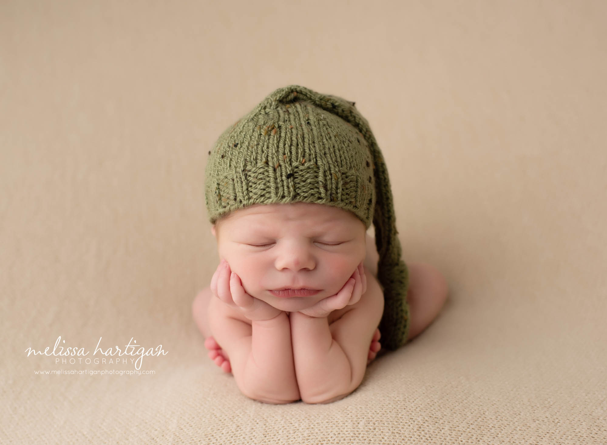 baby boy posed in froggy pose with green sleepy cap on posed newborn photography