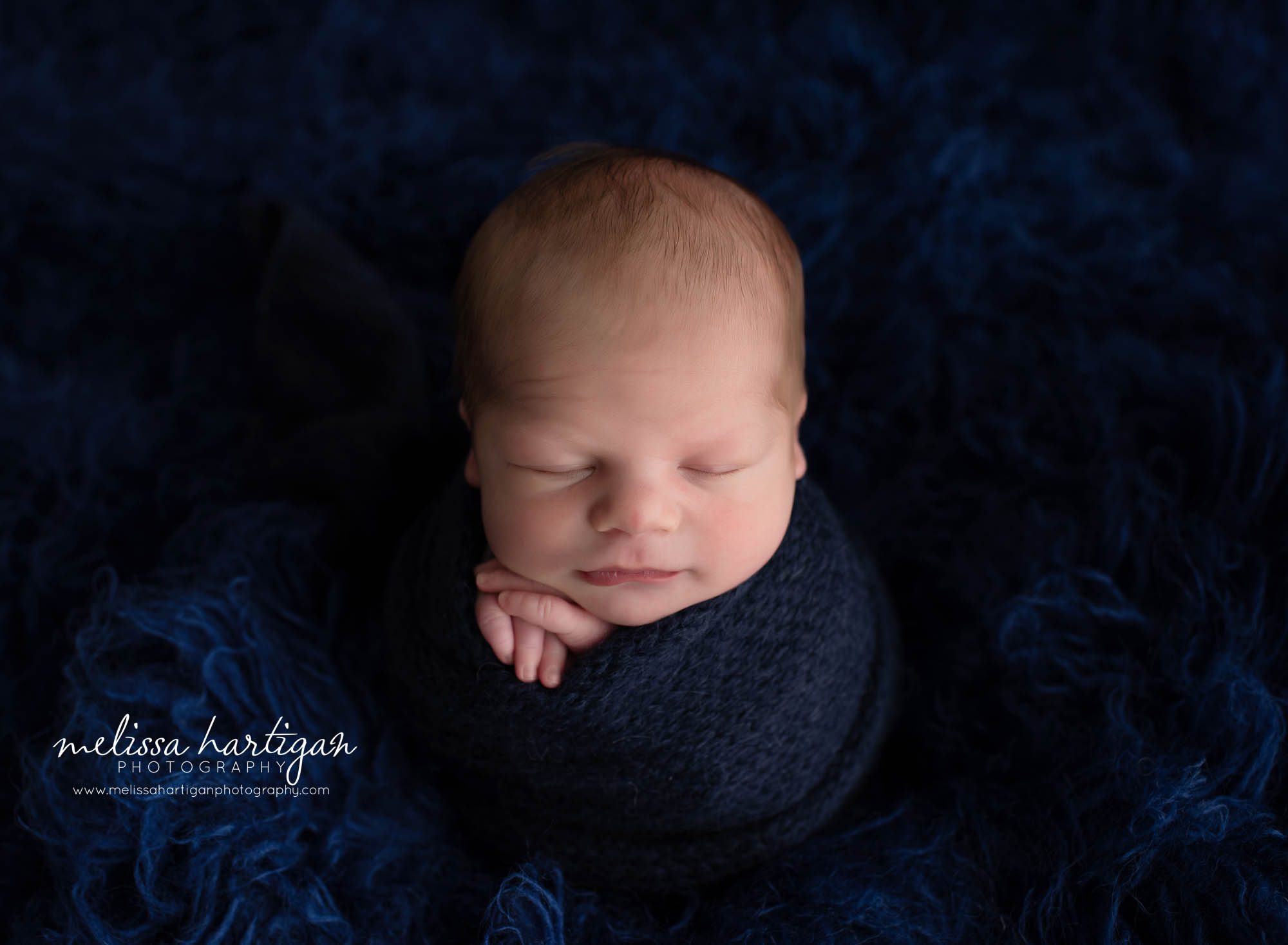 baby boy wrapped in navy blue knitted wrap on blue flokati ct newborn photography